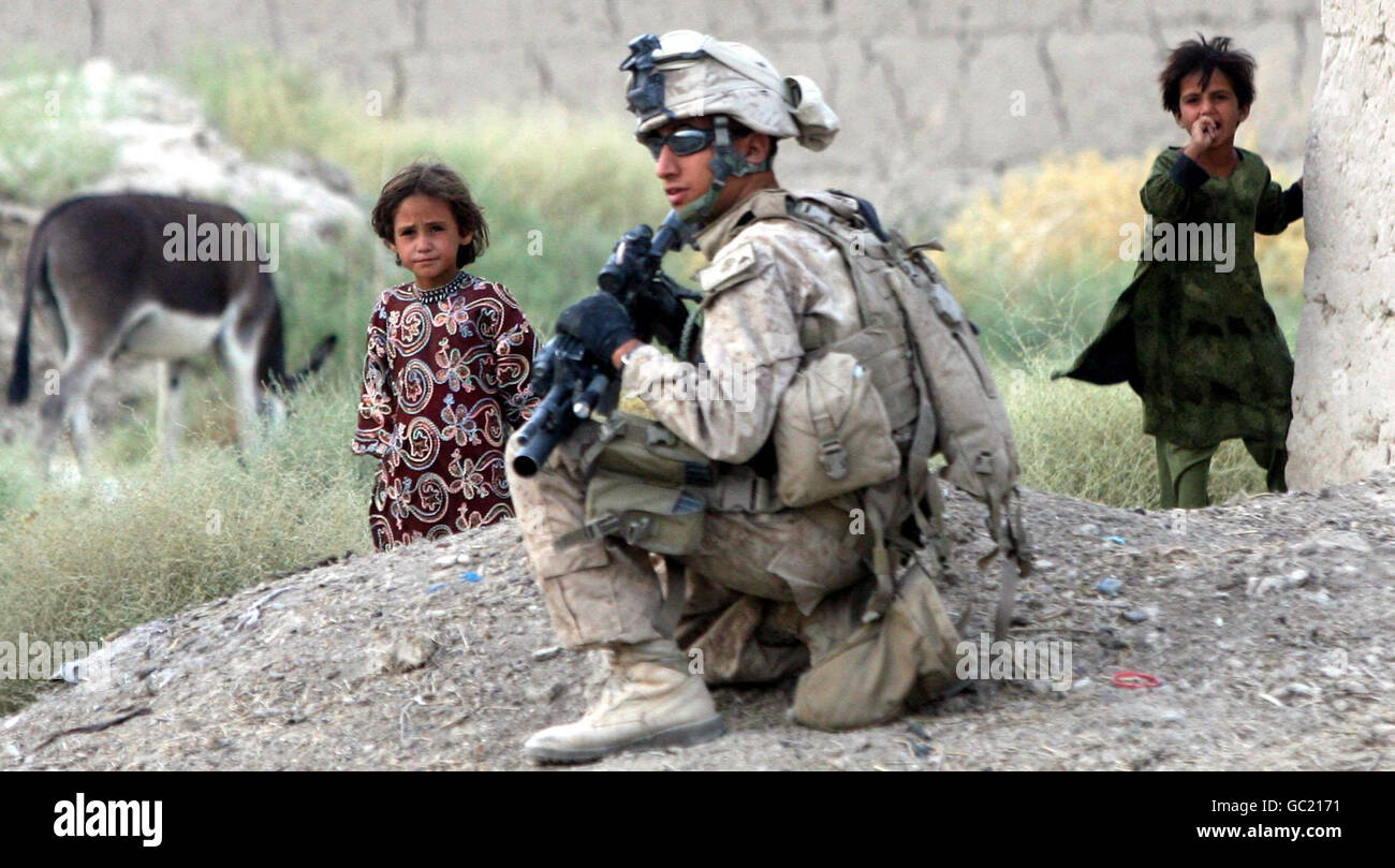 I bambini afghani guardano una marina americana durante una pattuglia a Khan Neshin, nella provincia di Helmand, in Afghanistan, il più a sud di qualsiasi esercito di coalizione e vicino al confine con il Pakistan. Foto Stock