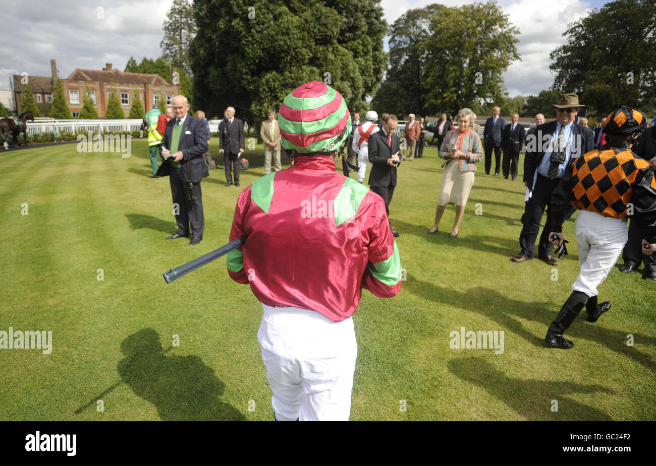 Jockey Kieren Fallon (centro) è il centro di attenzione come i jokey fanno il loro modo di sfilare anello per la prima gara a Lingfield Racecourse. Foto Stock