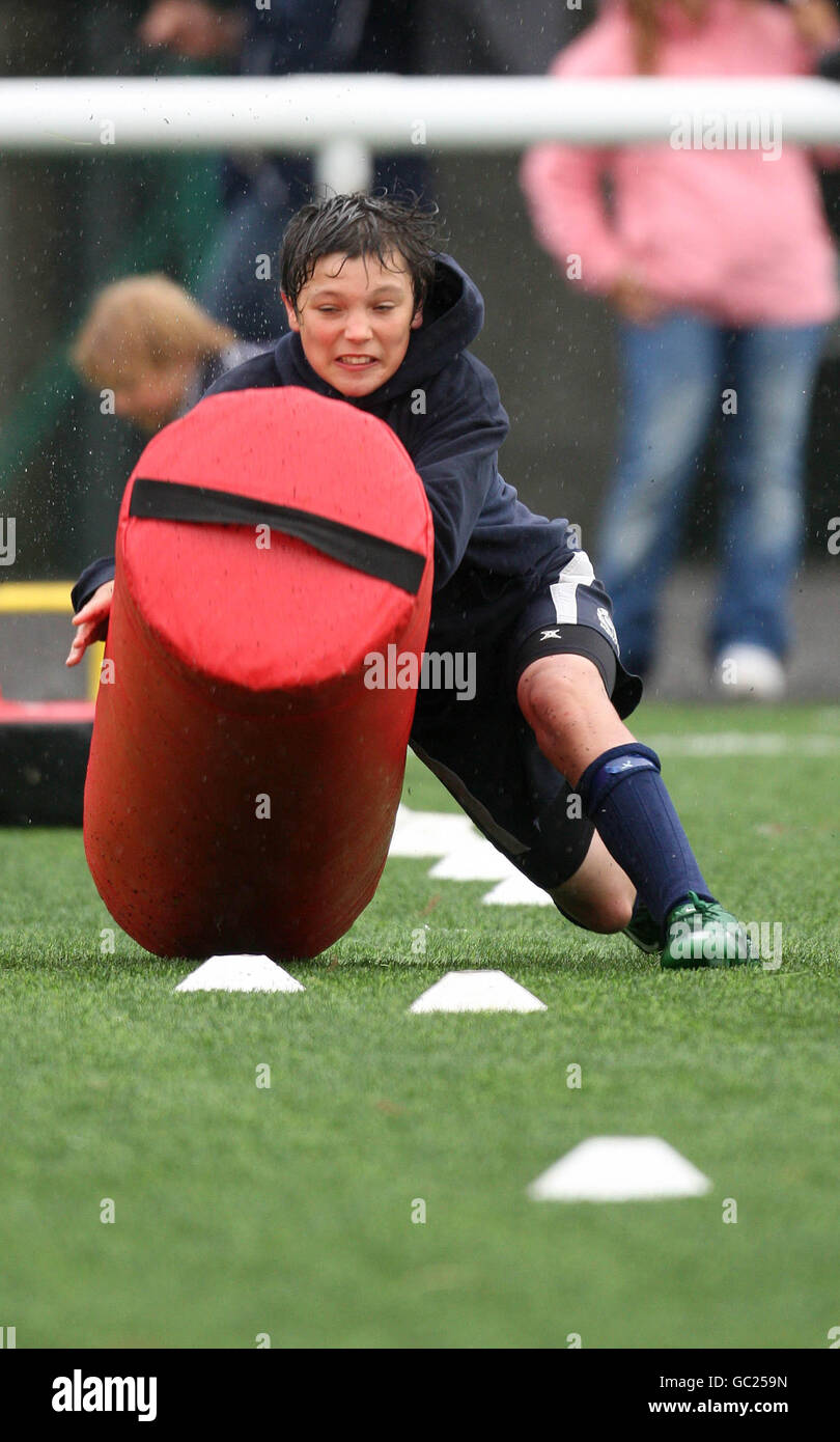 Un ragazzo tenta un percorso di ostacoli di rugby durante il campo estivo di rugby di Edimburgo a Murrayfield, Edimburgo. Foto Stock