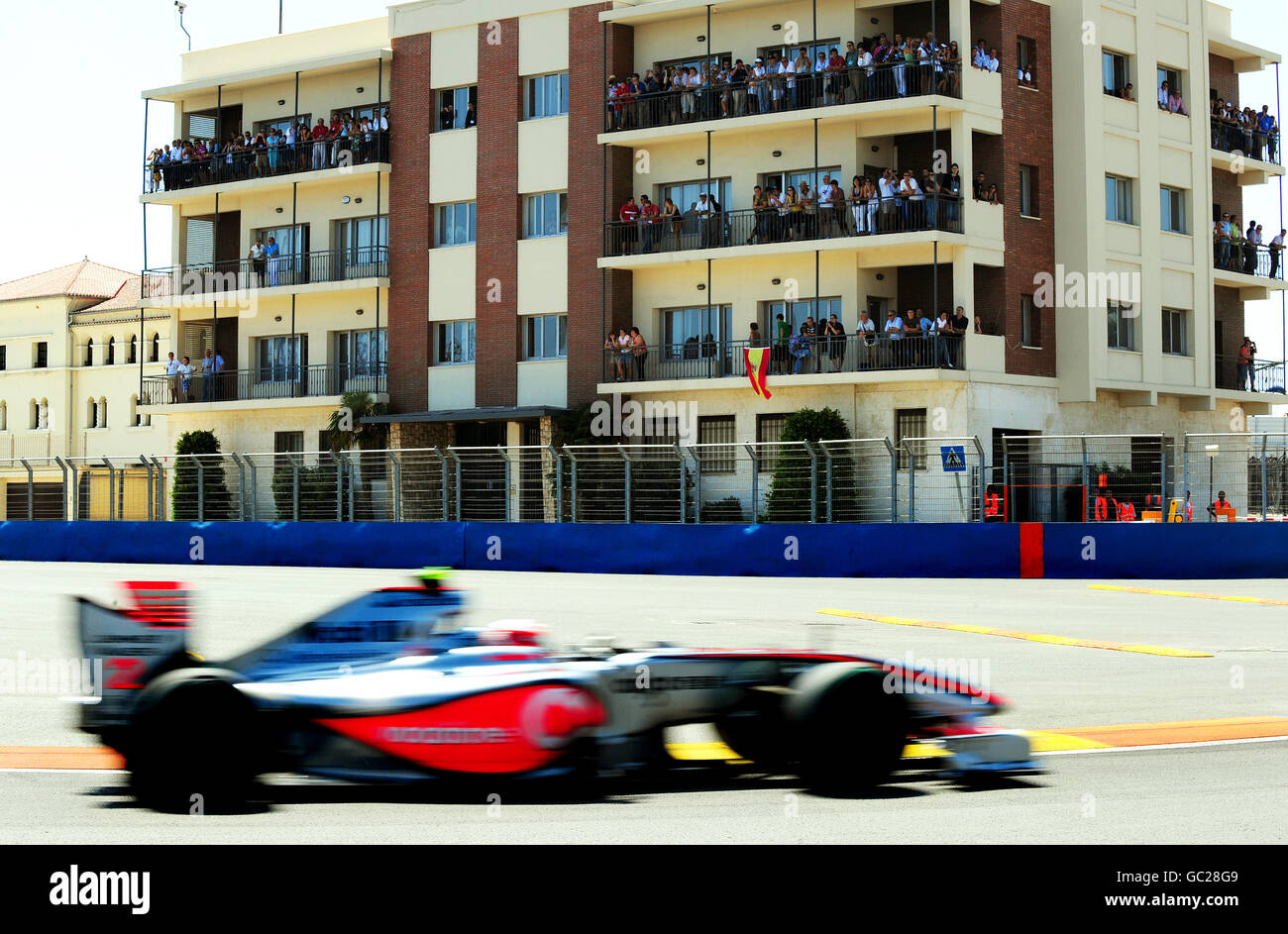 Gli spettatori guardano la McLaren Mercedes Heikki Kovalainen dalle loro verande durante le qualifiche al circuito di Valencia, in Spagna. Foto Stock