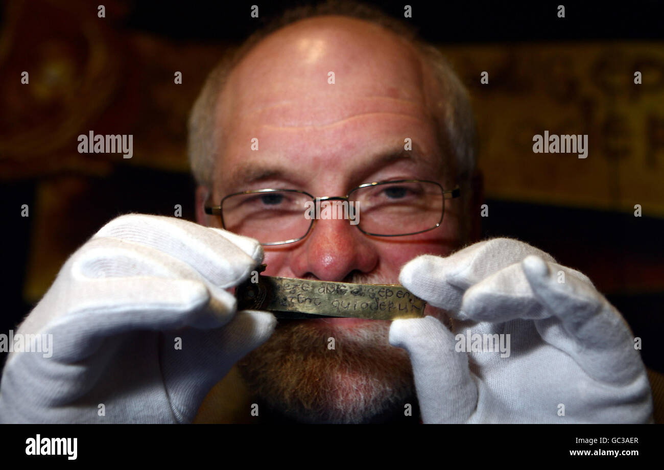 Una piccola striscia d'oro inscritta con una citazione di guerra dalla Bibbia è tenuta dal dottor Kevin Leahy del Portable Antiquities Scheme al Museo di Birmingham. E 'uno dei bastoni di oggetti trovati appena sotto la superficie di un campo coltivato nel sud Staffordshire nel mese di luglio. Foto Stock