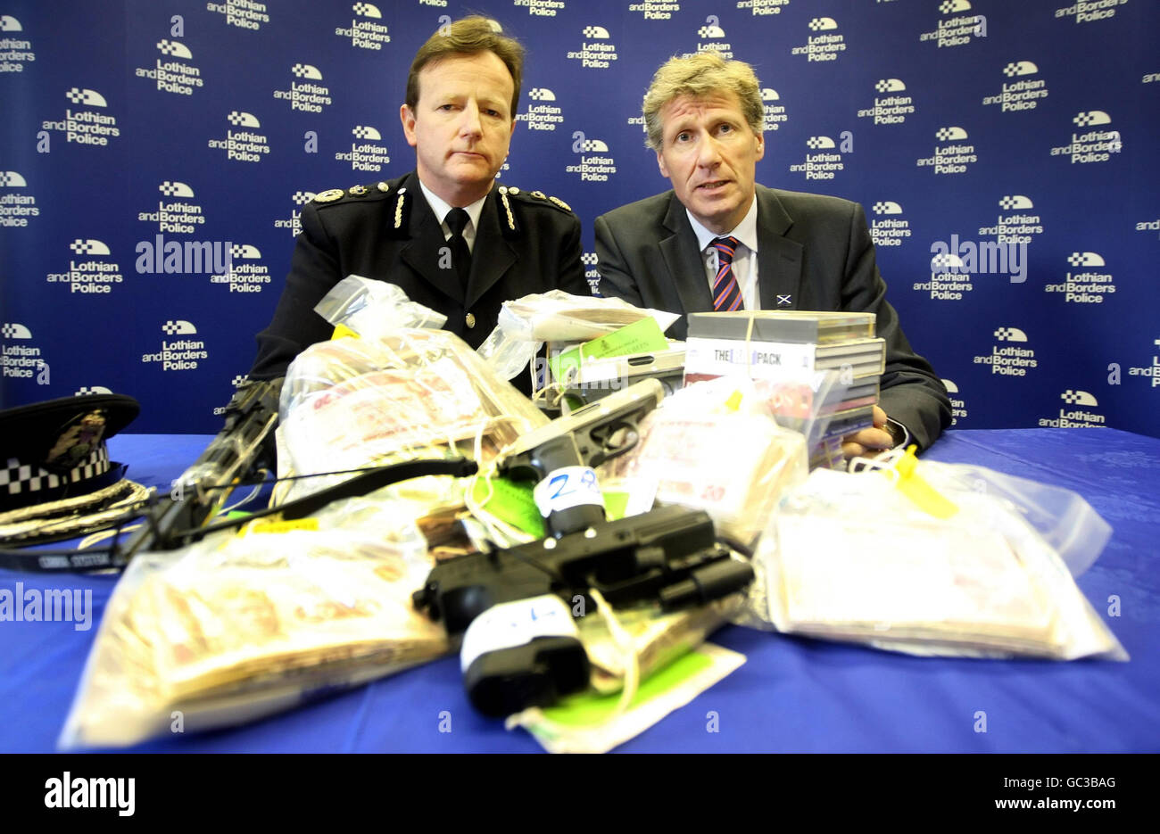 Il segretario alla giustizia Kenny MacAskill e il capo della polizia di Lothian e Borders Constable David Strang svelano una nuova strategia per affrontare le gravi reti di criminalità organizzata durante una conferenza stampa presso la stazione di polizia di St Leonard. La coppia è raffigurata con armi, merci contraffatte e droghe, sequestrate in operazioni. Foto Stock