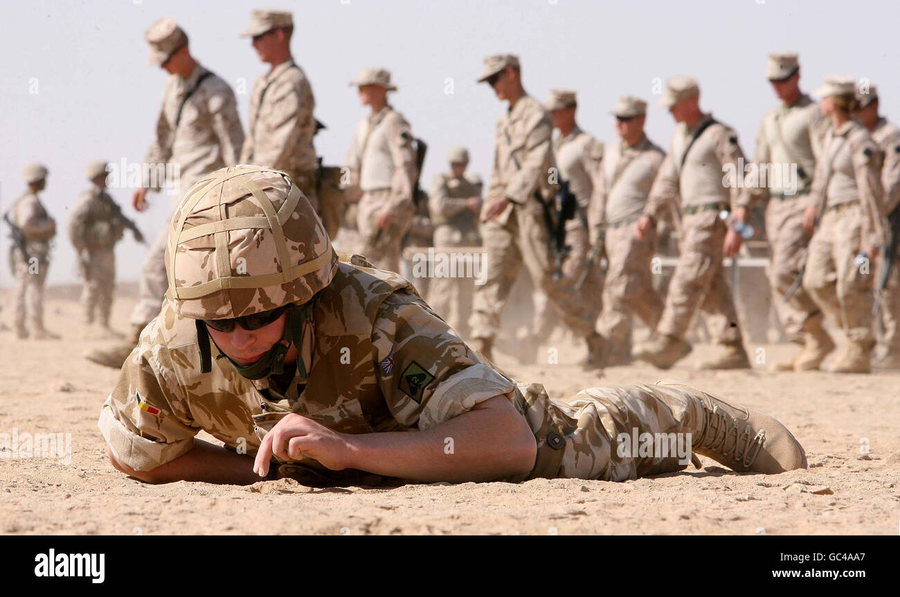 Un soldato dell'esercito britannico in un esercizio di addestramento alla ricerca di dispositivi esplosivi improvvisati (IED) a Camp Bastion in Afghanistan con i Marines americani in lontananza. Foto Stock