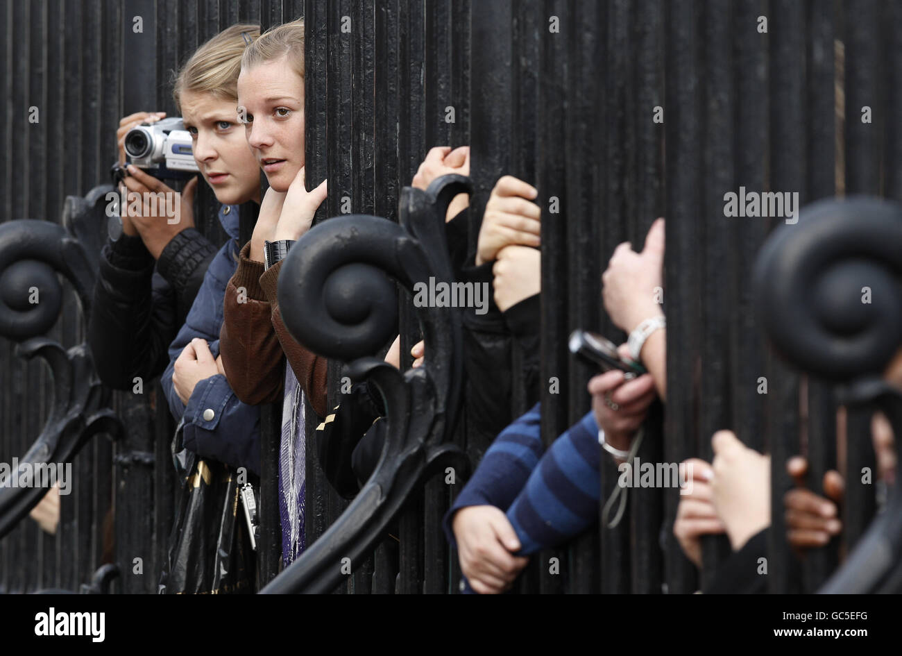 I turisti e gli onlooker si lanciano attraverso le porte di Buckingham Palace mentre attendono la regina Elisabetta II della Gran Bretagna e il presidente indiano Pratibha Patil al lancio dei XIX Giochi del Commonwealth a Londra. Foto Stock