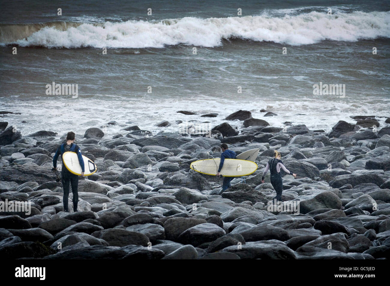 I surfisti si dirigano verso il mare in mute a Putsborough, nel Devon settentrionale, dove forti venti hanno causato grandi ondate. Foto Stock