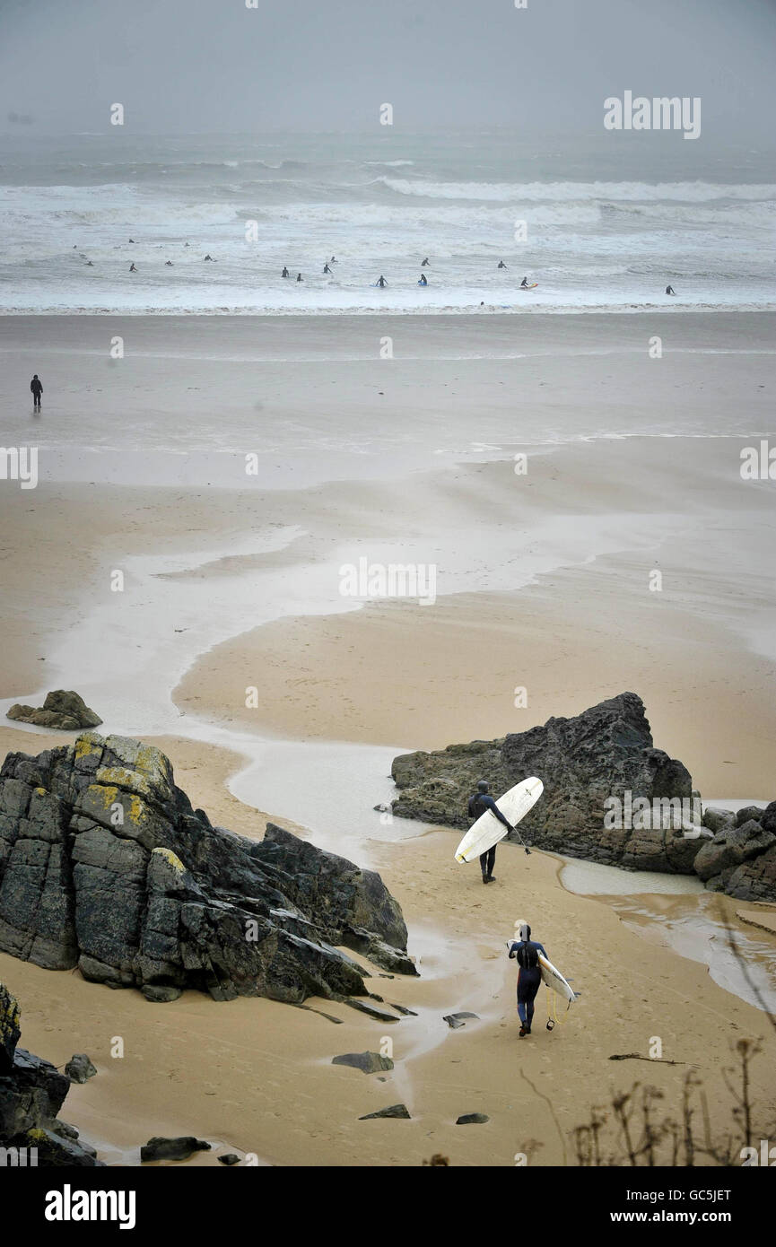 I surfisti si dirigano verso il mare in mute a Putsborough, nel Devon settentrionale, dove forti venti hanno causato grandi ondate. Foto Stock