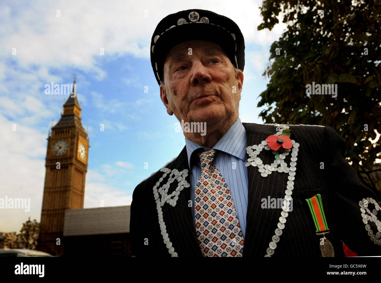 Un Signore vestito in costume tradizionale indossa un papavero prima di un silenzio di due minuti per commemorare l'Armistice Day in Parliament Square, Londra. Foto Stock