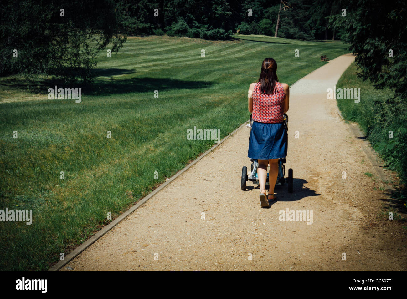 Madre con bambino trasporto passeggiate nel percorso sul parco. Retrò foto stilizzata. Madre con bambino trasporto passeggiate nel percorso sul parco. Retr Foto Stock