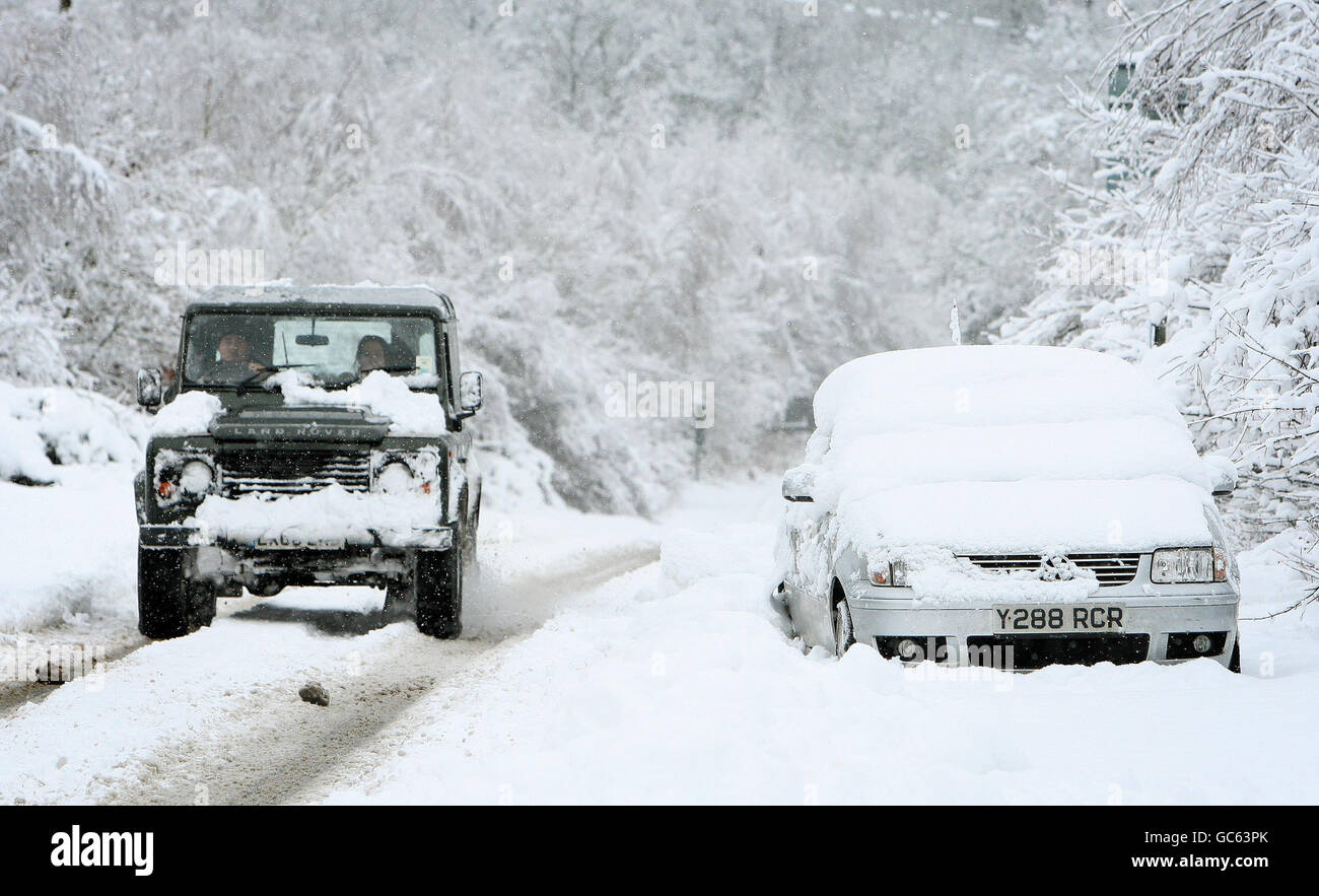 Un'auto abbandonata si trova sul lato di una strada vicino alla A3 in Surrey, come una fresca raffica di neve durante la notte ha portato nuova miseria per i viaggiatori. Foto Stock