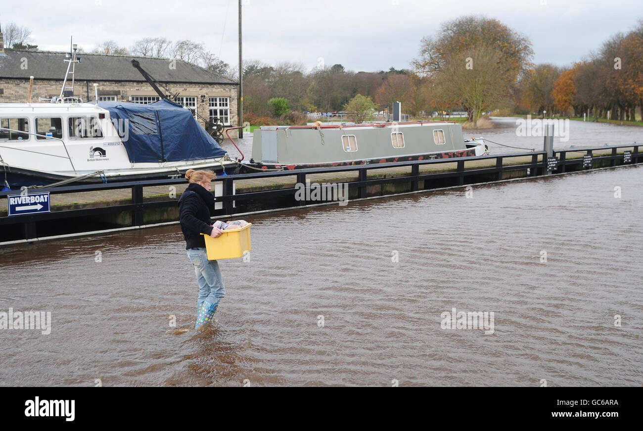 Amy Gaskell porta la sua casa per lo shopping attraverso le crescenti acque alluvionali del fiume Ouse a Naburn, York, come gli esperti avvertono che il deflusso è previsto per continuare nel nord dell'Inghilterra, nel Galles nord-occidentale e nella Scozia occidentale. Foto Stock