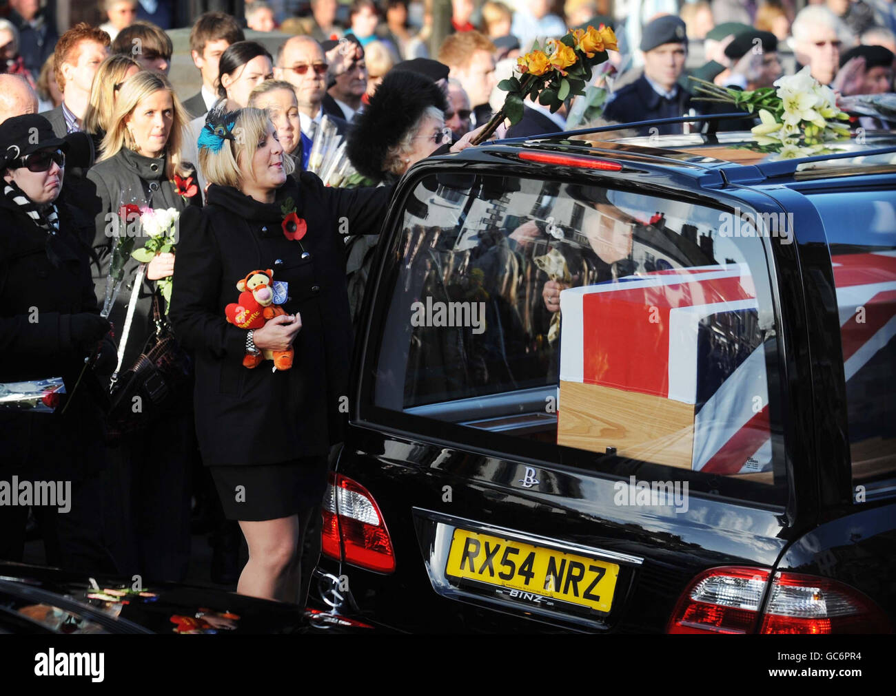 Nicola, la moglie del caporale Loren Marlton-Thomas si reca in avanti per mettere i fiori su un cuore come porta la bara del marito attraverso la città Wiltshire di Wootton Bassett dopo il suo rimpatrio a RAF Lyneham, Wiltshire. Foto Stock