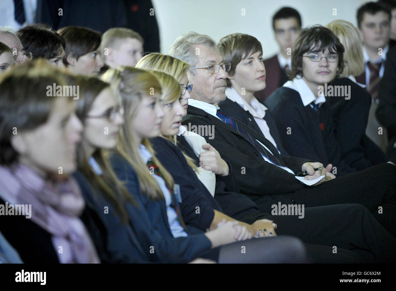 Sir Ian McKellan siede con gli alunni della Severn vale School di Gloucester mentre guarda una rappresentazione eseguita dagli alunni della scuola circa con un messaggio anti-omofobico di bullismo. Foto Stock