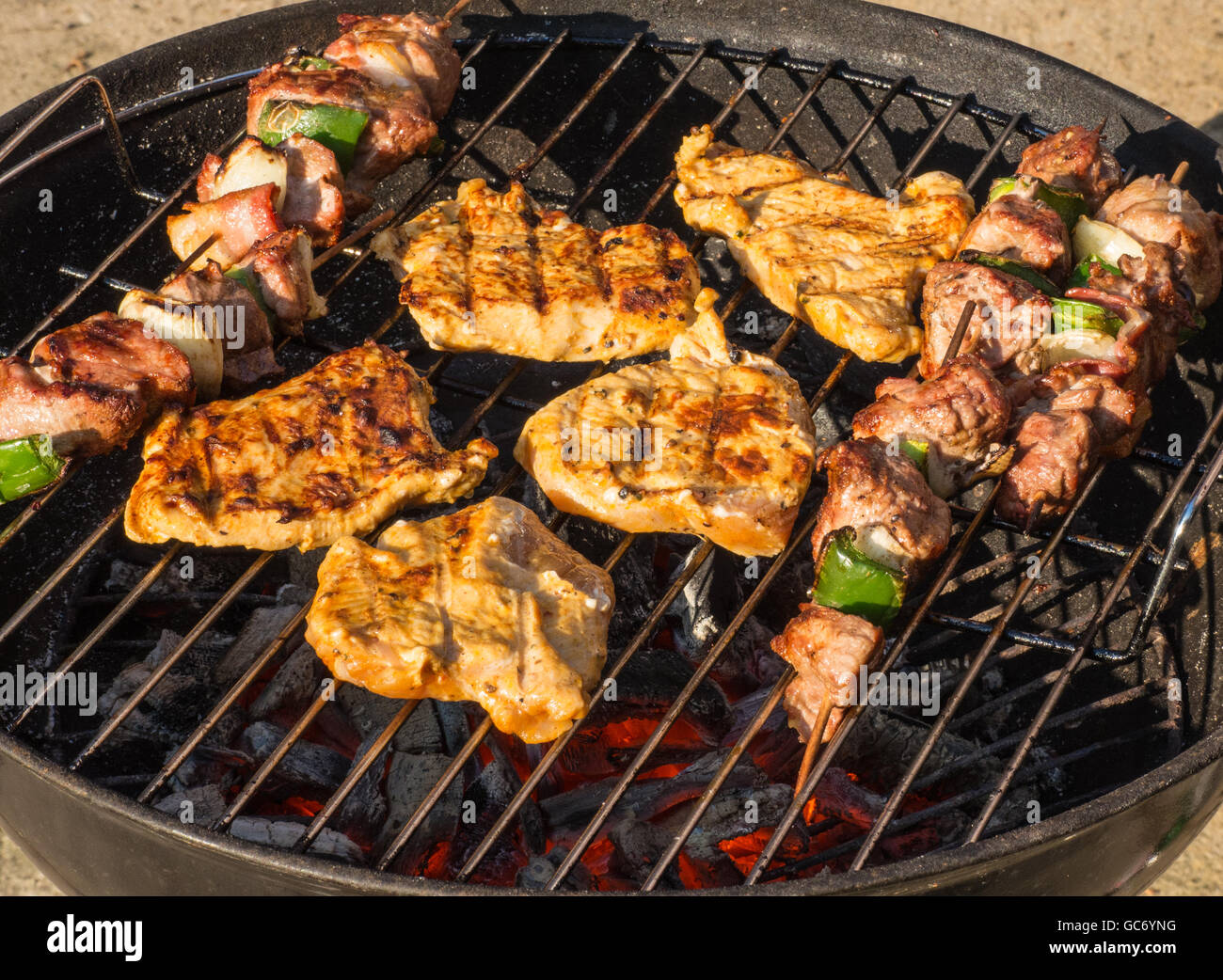 Barbecue con shish kebab e bistecche alla griglia su carbone incandescente Foto Stock