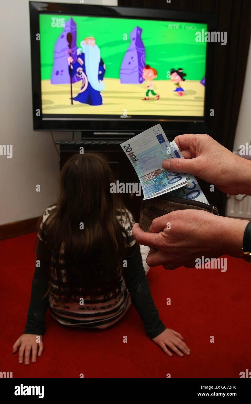IMMAGINE POSATA DAL MODELLO. Un bambino guarda la televisione e una madre conta i soldi nella sua borsa a Dublino il giorno di bilancio in cui le indennità del bambino devono essere abbattute fino al 10%, riducendo i pagamenti mensili di più di 16 euro. Foto Stock