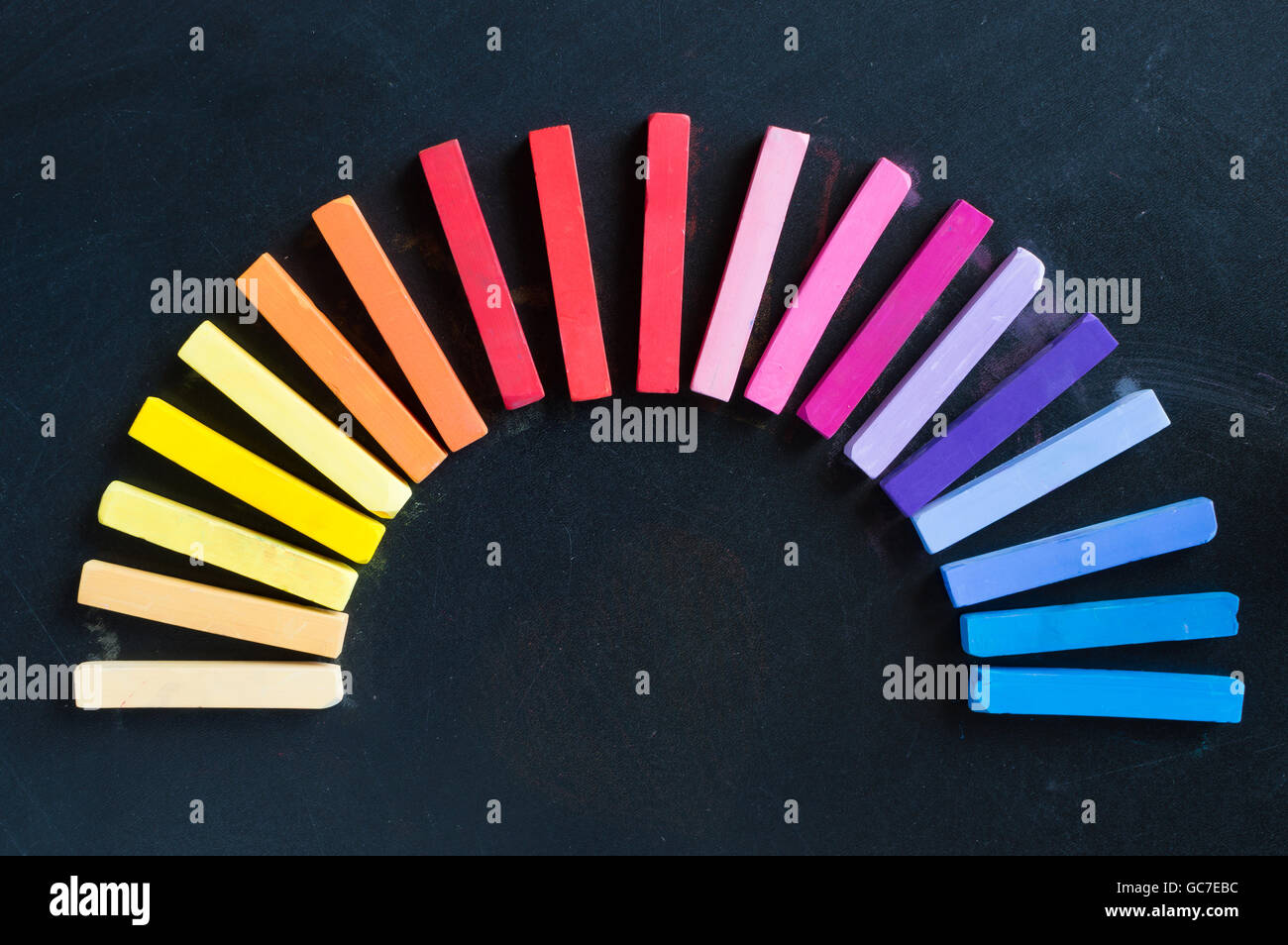 Arcobaleno di gessi colorati schierate arrotondato sul cerchio sullo sfondo della lavagna Foto Stock