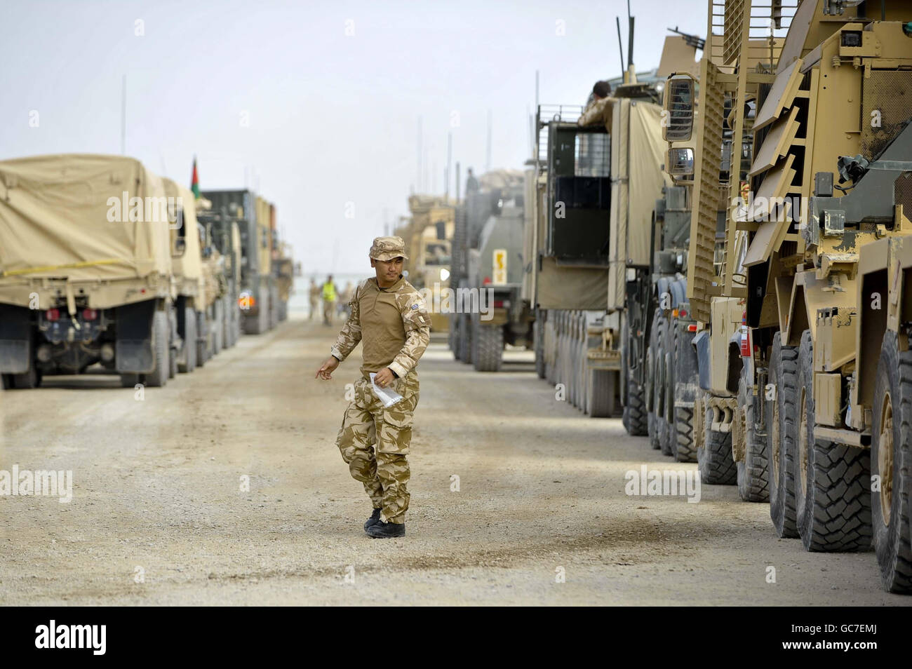 Un Gurkha cammina tra due linee di veicoli che si preparano a effettuare una pattuglia logistica di combattimento (CLP), insieme alle forze americane e all'esercito nazionale afgano per la prima volta sull'operazione Herick 11, trasportando forniture essenziali dal Bastione del campo a Sangin, provincia di Helmand, Afghanistan in un convoglio di veicoli del 100. Foto Stock