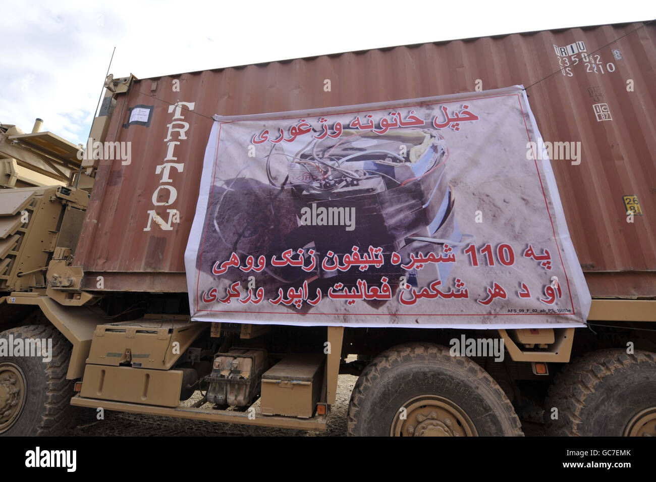 Un banner sul lato di un autocarro militare che sta conducendo una pattuglia logistica di combattimento (CLP), accanto alle forze americane e all'esercito nazionale afgano per la prima volta sull'operazione Herick 11, trasportando forniture essenziali dal Bastione del campo a Sangin, provincia di Helmand, Afghanistan in un convoglio di 100 veicoli. Il messaggio è uno dei tanti che vengono posti sui veicoli del convoglio che trasmettono messaggi al popolo afghano. Quello raffigurato suggerisce al messaggio in Pashtun che la gente dovrebbe segnalare tutto il sospetto che vedono e denominare un numero di telefono. Foto Stock