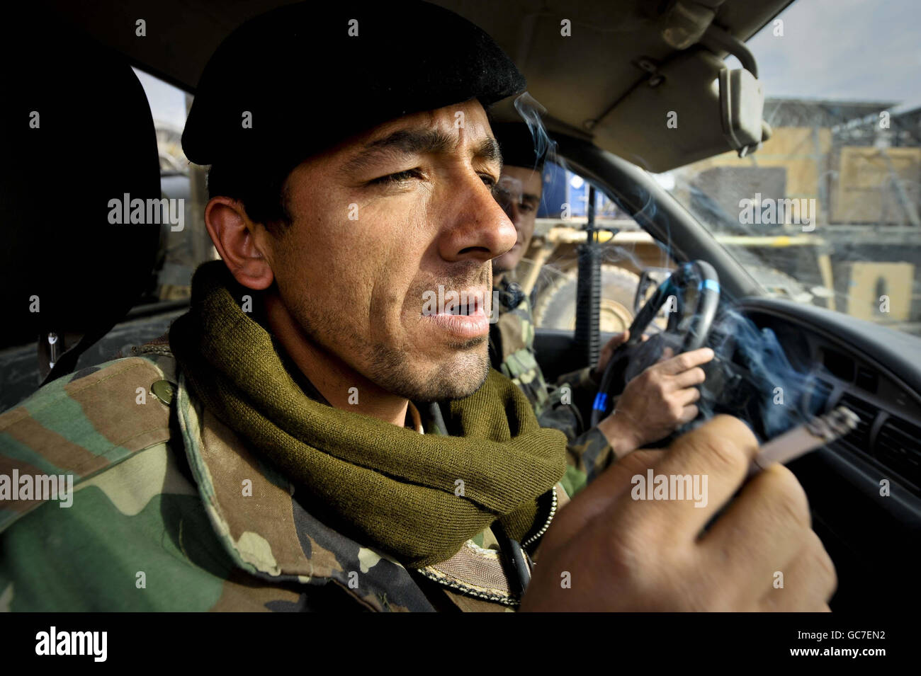 Un soldato dell'esercito nazionale afghano fuma una sigaretta a bordo di un veicolo 4x4 mentre lui e altre truppe ANA si preparano a realizzare una pattuglia logistica di combattimento (CLP), insieme alle forze americane e britanniche per la prima volta sull'operazione Herrick 11, trasportando forniture essenziali dal Bastione del campo a Sangin, Provincia di Helmand, Afghanistan in un convoglio di 100 veicoli. Foto Stock