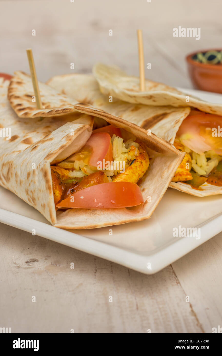 Burrito riempito con pollo, peperoni, riso e pomodoro con la salsa sul lato Foto Stock