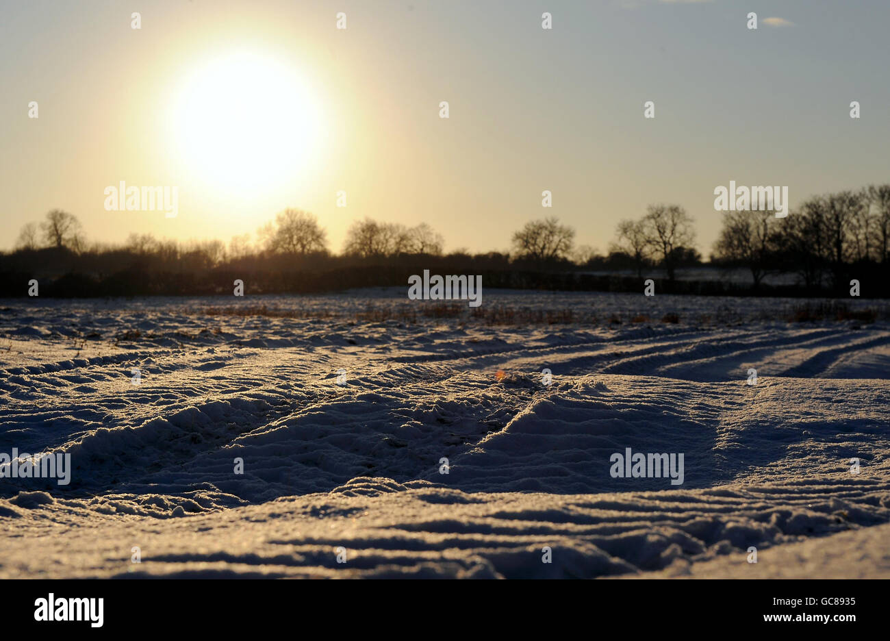 Il sole comincia a tramontare su un campo innevato a Barkby, nel Leicestershire. Foto Stock