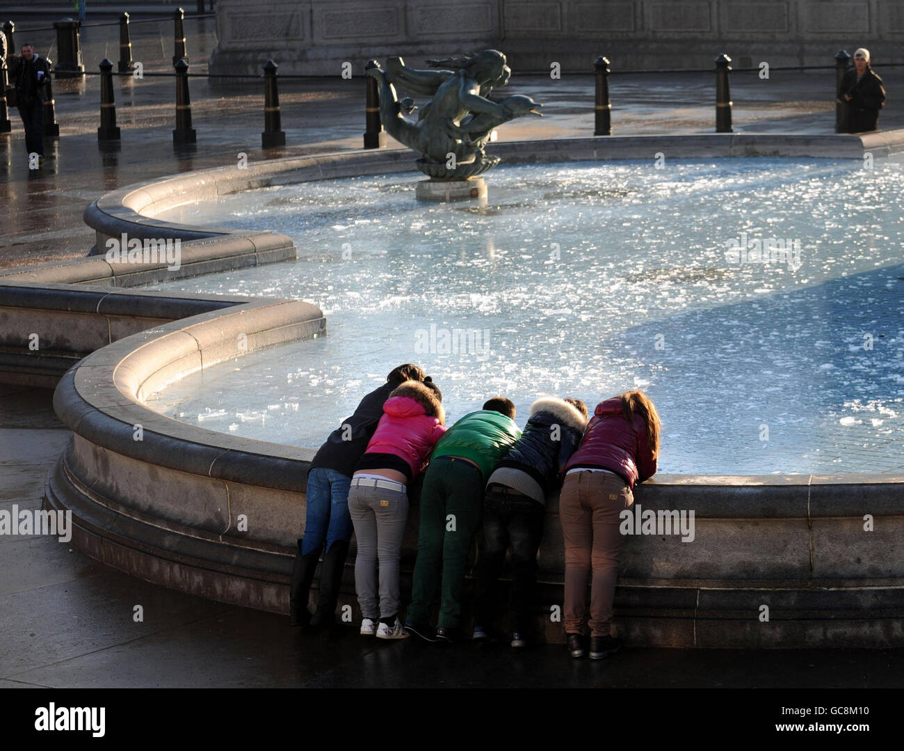 I visitatori di Trafalgar Square a Londra indagano sulle piscine ghiacciate dopo una surgelante notte. Foto Stock