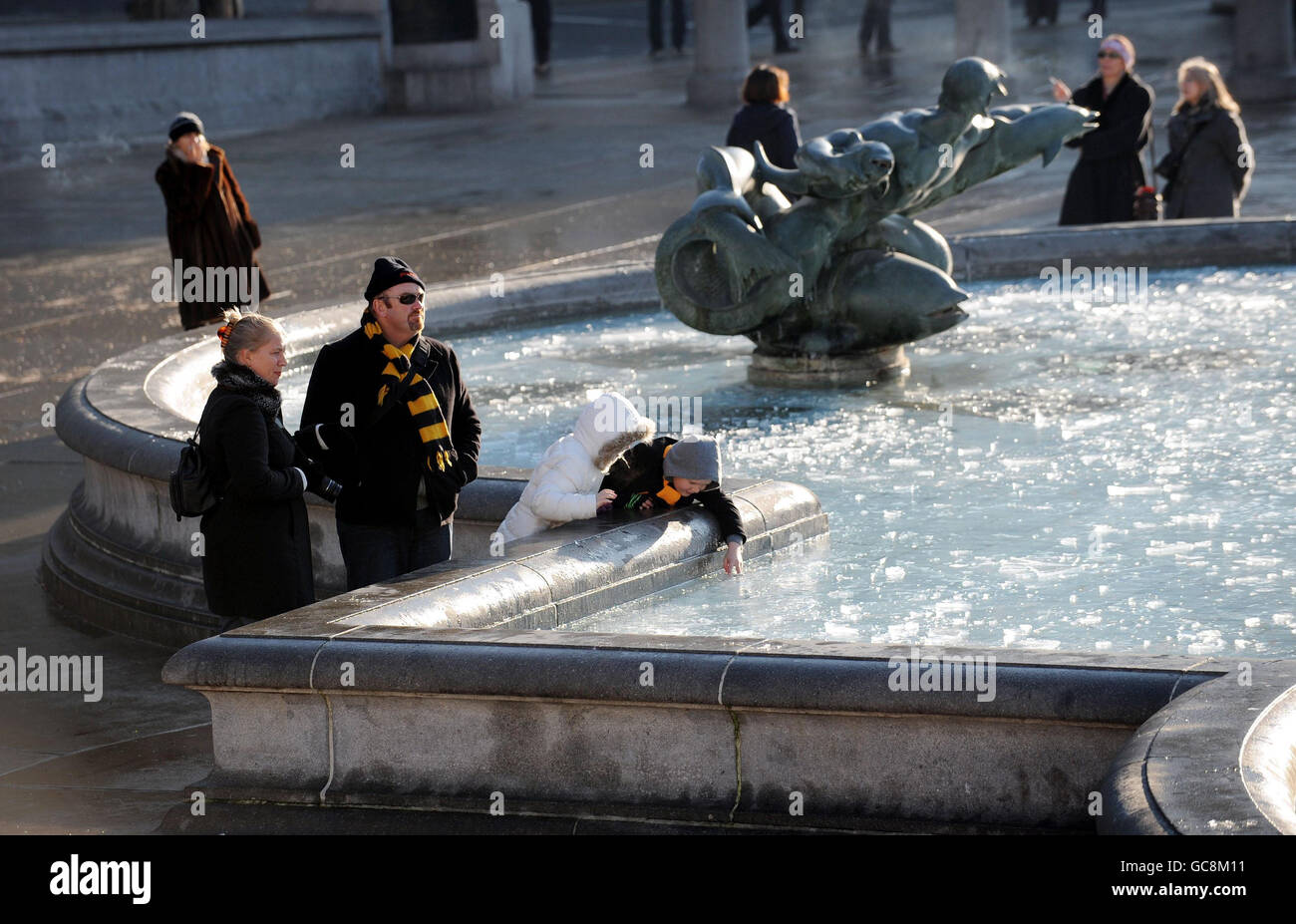 I visitatori di Trafalgar Square a Londra indagano sulle piscine ghiacciate dopo una surgelante notte. Foto Stock