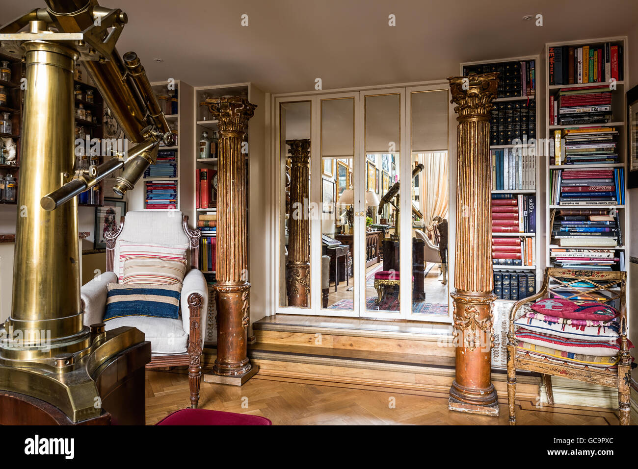 Recuperati pilastri con librerie e porta in mirroring in Londra appartamento pieni di curiosità di antiquariato Foto Stock