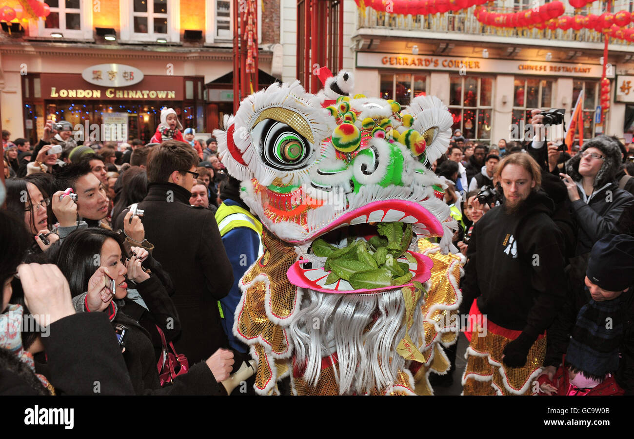 La gente celebra l'inizio dei festeggiamenti per il nuovo anno cinese mentre un leone cinese tradizionale si fa strada attraverso le strade affollate di Chinatown, Londra. Foto Stock