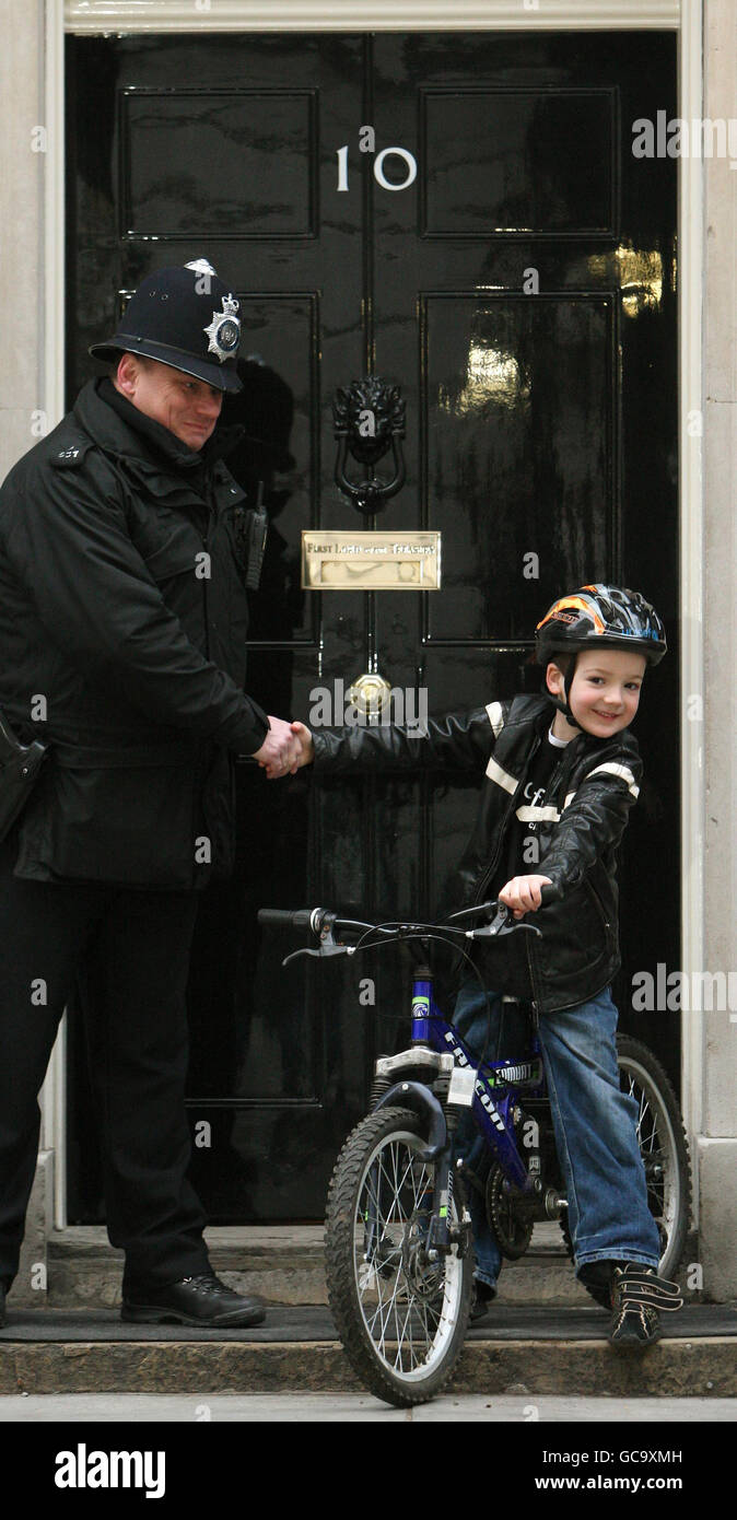 Charlie Simpson, 7 anni, da Fulham, West London, che ha raccolto oltre 160,000 persone per l'appello dei bambini del terremoto di Haiti dell'Unicef con un giro in bicicletta sponsorizzato, scuote le mani con un poliziotto fuori 10 Downing Street, Westminster, Londra. Foto Stock