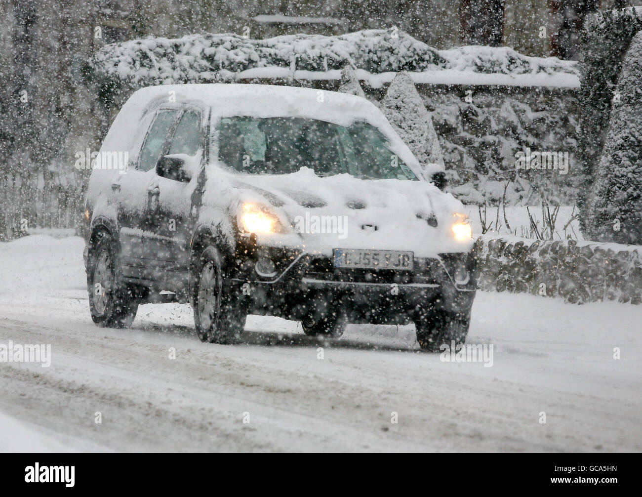 Un autista si fa strada attraverso Great Chart vicino Ashford, Kent, dopo una notte di forte caduta di neve. Foto Stock