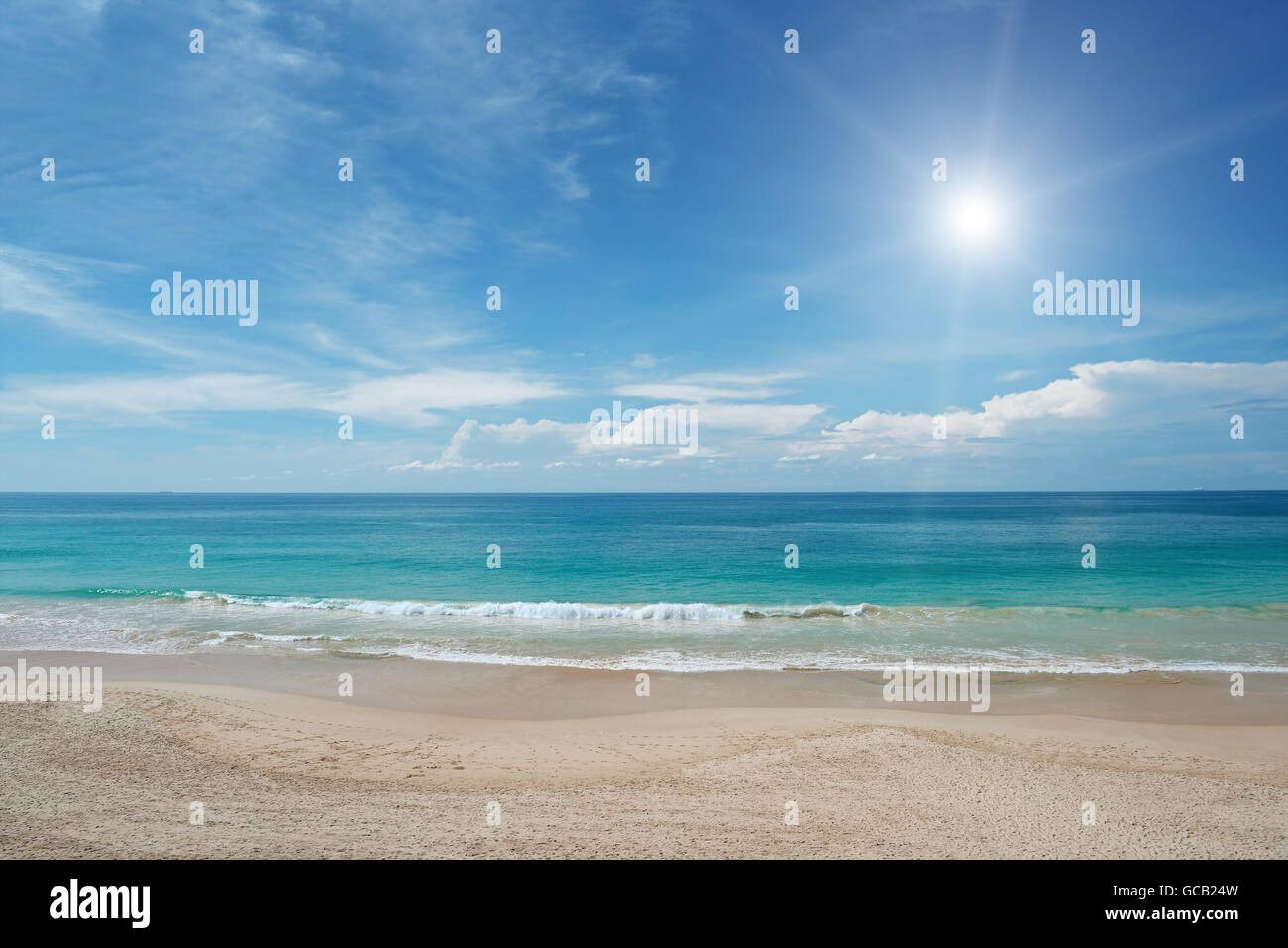 Spiaggia di sabbia e il sole nel cielo blu Foto Stock