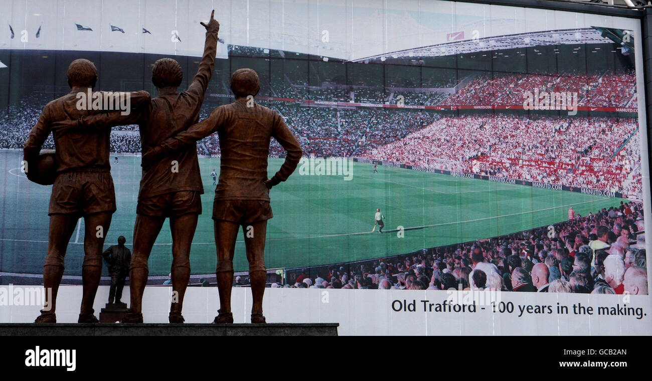 Un poster all'esterno dello stadio Old Trafford di Manchester United che  celebra i 100 anni dello stadio Old trafford è raffigurato anche la Statua  della Denis Law, Sir Bobby Charlton e George