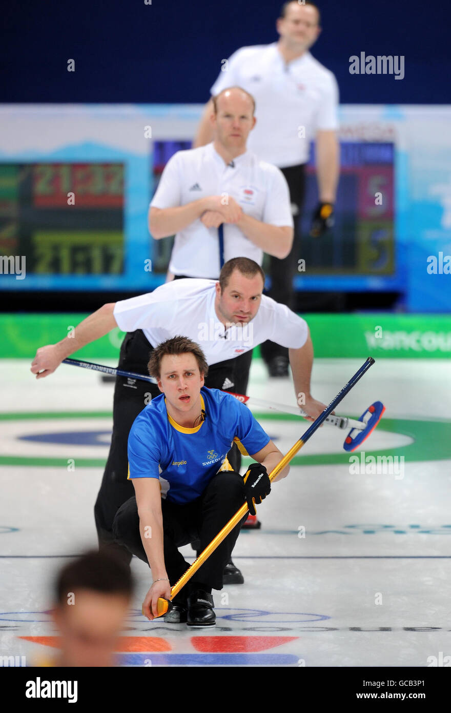 Fredrik Lindberg (in basso) in Svezia è sorvegliato da Euan Byers, Ewan MacDonald e Pete Smith (in alto) in Gran Bretagna durante la gara di curling maschile contro la Svezia durante le Olimpiadi invernali del 2010 presso il Vancouver Olympic Centre, Vancouver, Canada. Foto Stock