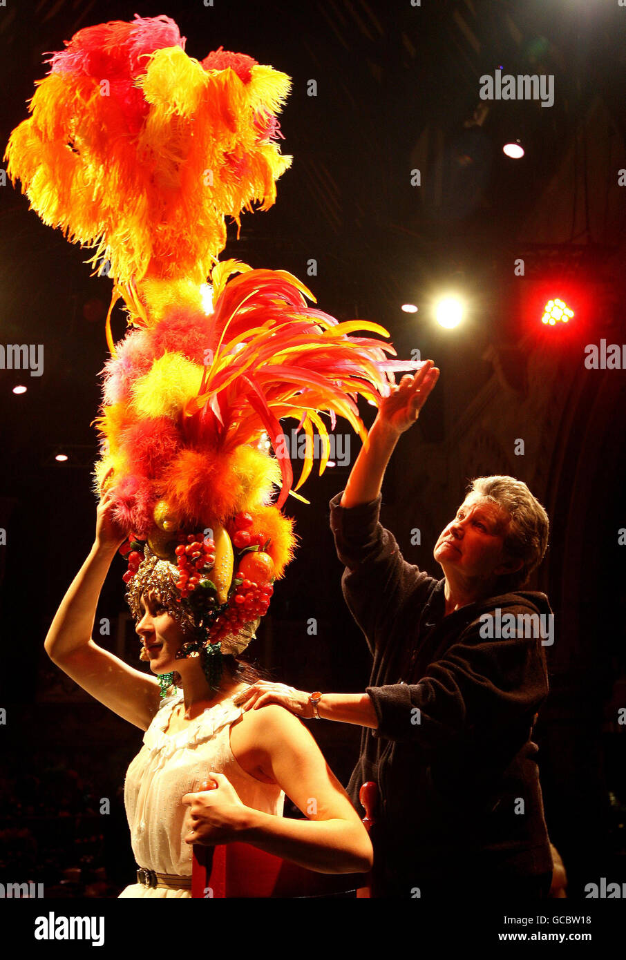 Il Costumier Annie Galbraith (a destra) regola un capo-vestito 'Carmen Miranda' originariamente indossato dalla sosia femminile Danny la Rue, parte di una collezione dei suoi 90 costumi e camici, che sono offerti all'asta presso il Brick Lane Music Hall, Londra orientale, venerdì 12 marzo. Foto Stock