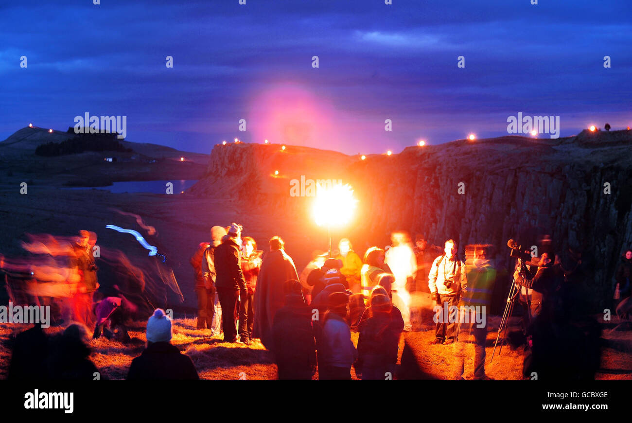 Gli spettatori si riuniscono attraverso le colline di Pennine tra Newcastle e Carlisle mentre i volontari che portano fiammeggianti torce illuminano il percorso del Muro di Adriano. Foto Stock