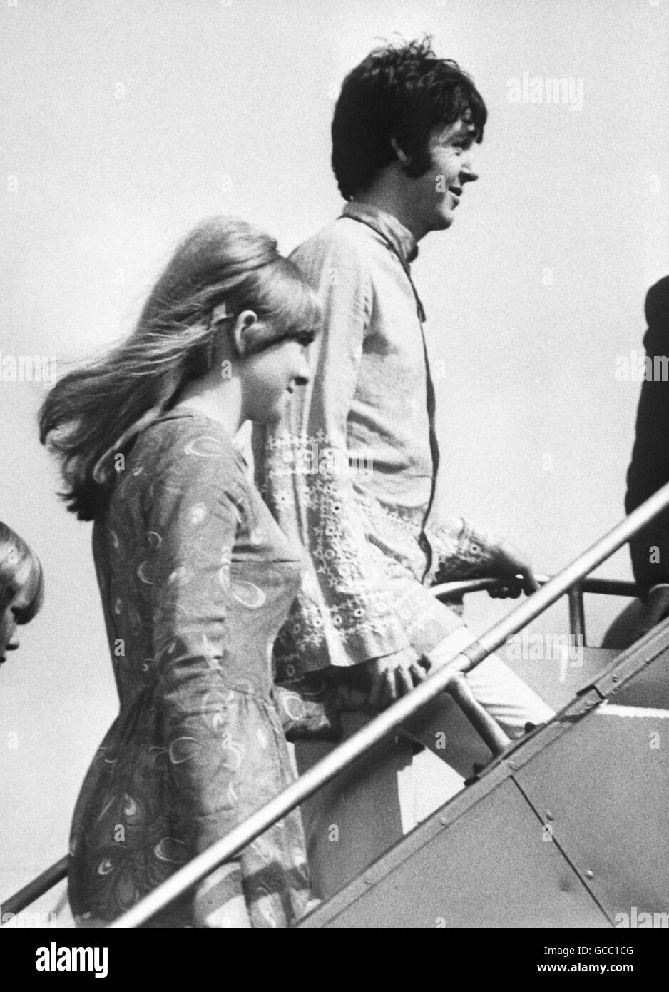 Paul McCartney, dei Beatles, in una tunica ricamata, e la sua fidanzata Jane Asher, salendo a bordo di un aereo di linea all'aeroporto di Heathrow per una vacanza ad Atene, in Grecia. Foto Stock