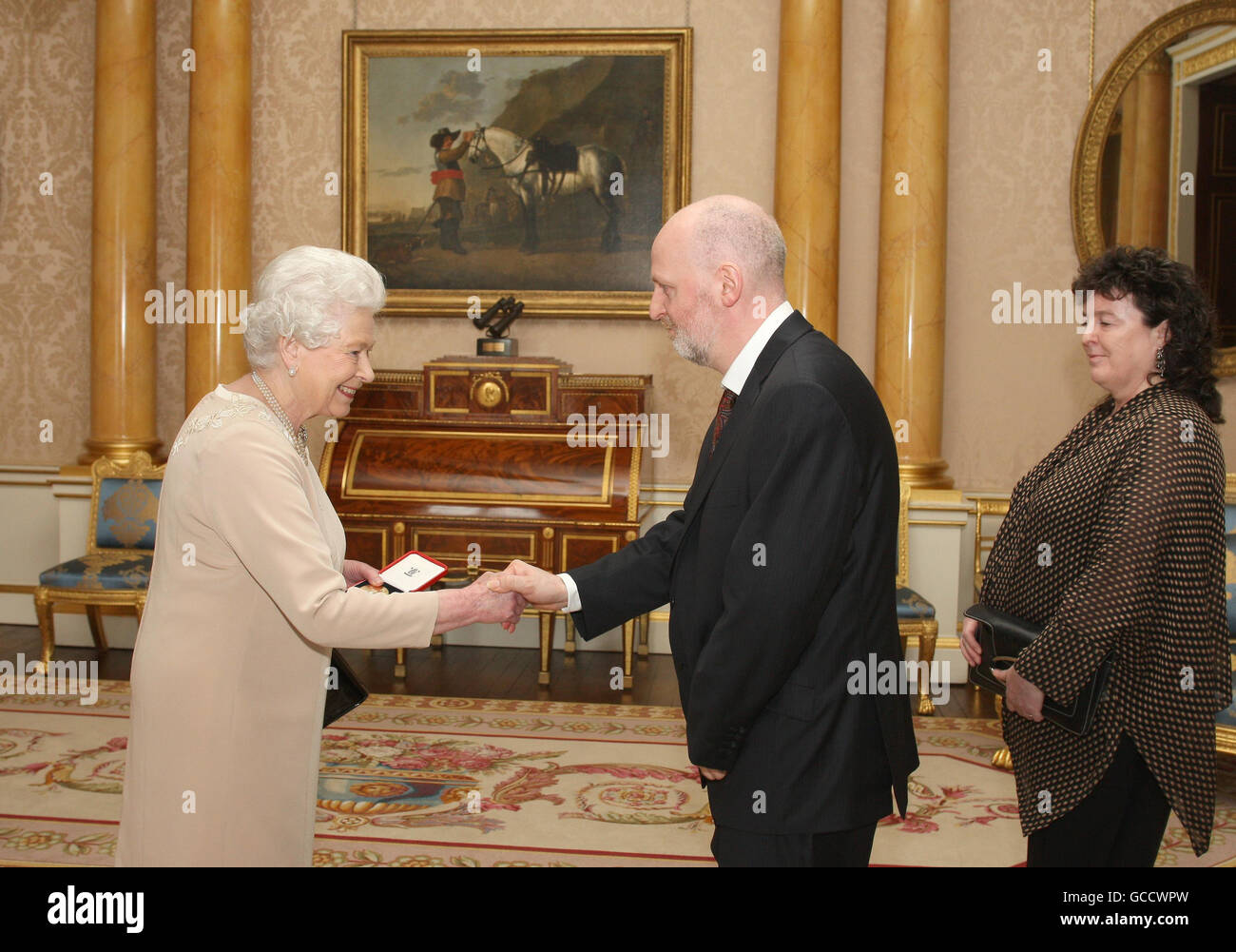 La regina britannica Elizabeth II presenta Donald Paterson, dalla Scozia, con la medaglia d'oro della regina per la poesia, guardata dal poeta Laureate Carol Ann Duffy, durante un'udienza a Buckingham Palace, Londra. Foto Stock