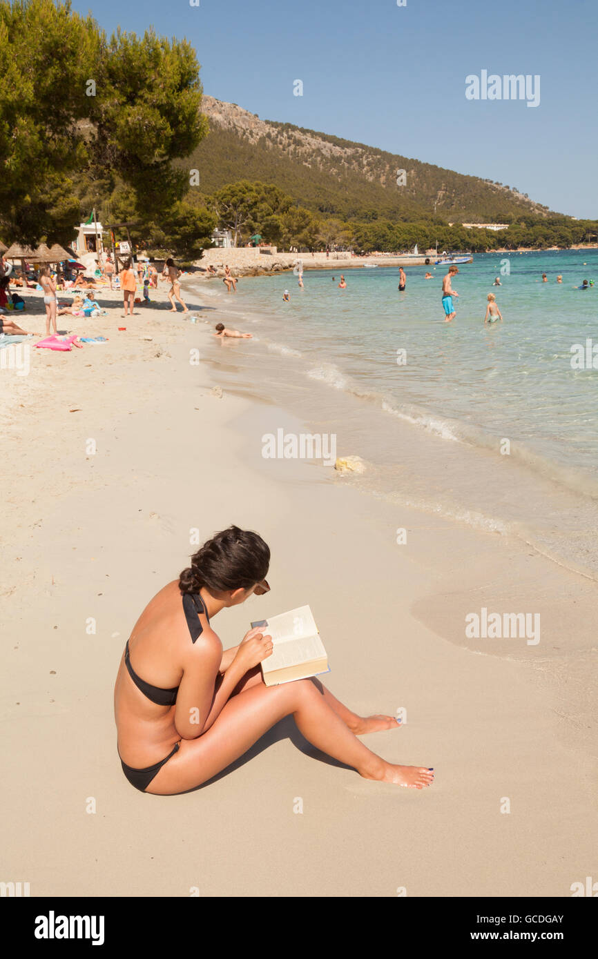 Giovane donna leggendo un libro seduti sulla spiaggia, Maiorca ( Mallorca ),Spagna Europa Foto Stock