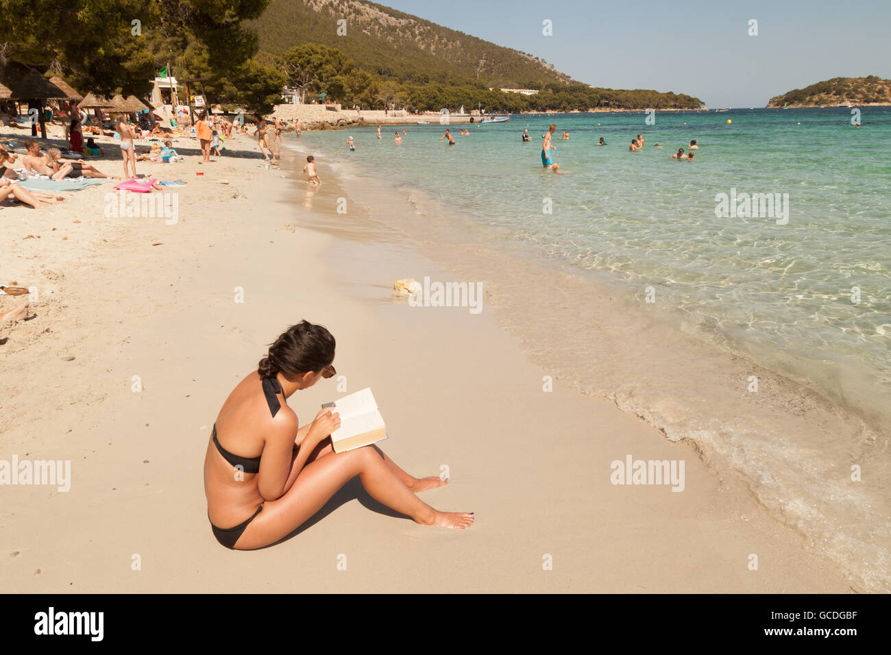 Giovane donna leggendo un libro seduti sulla spiaggia, Maiorca ( Mallorca ),Spagna Europa Foto Stock