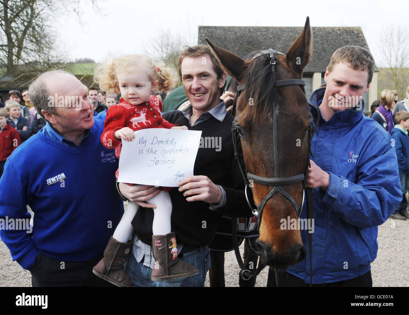 Non spingere, jockey Tony McCoy sua figlia Eve di 2 anni con l'allenatore Jonjo o'Neill (a sinistra) e sposare Alan Berry (a destra) durante la sfilata al Plow Inn a Ford, Temple Guiting. Foto Stock