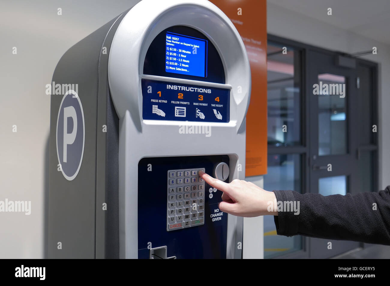 Donna preme la piastra numero di auto per pagare i biglietti per il parcheggio Foto Stock
