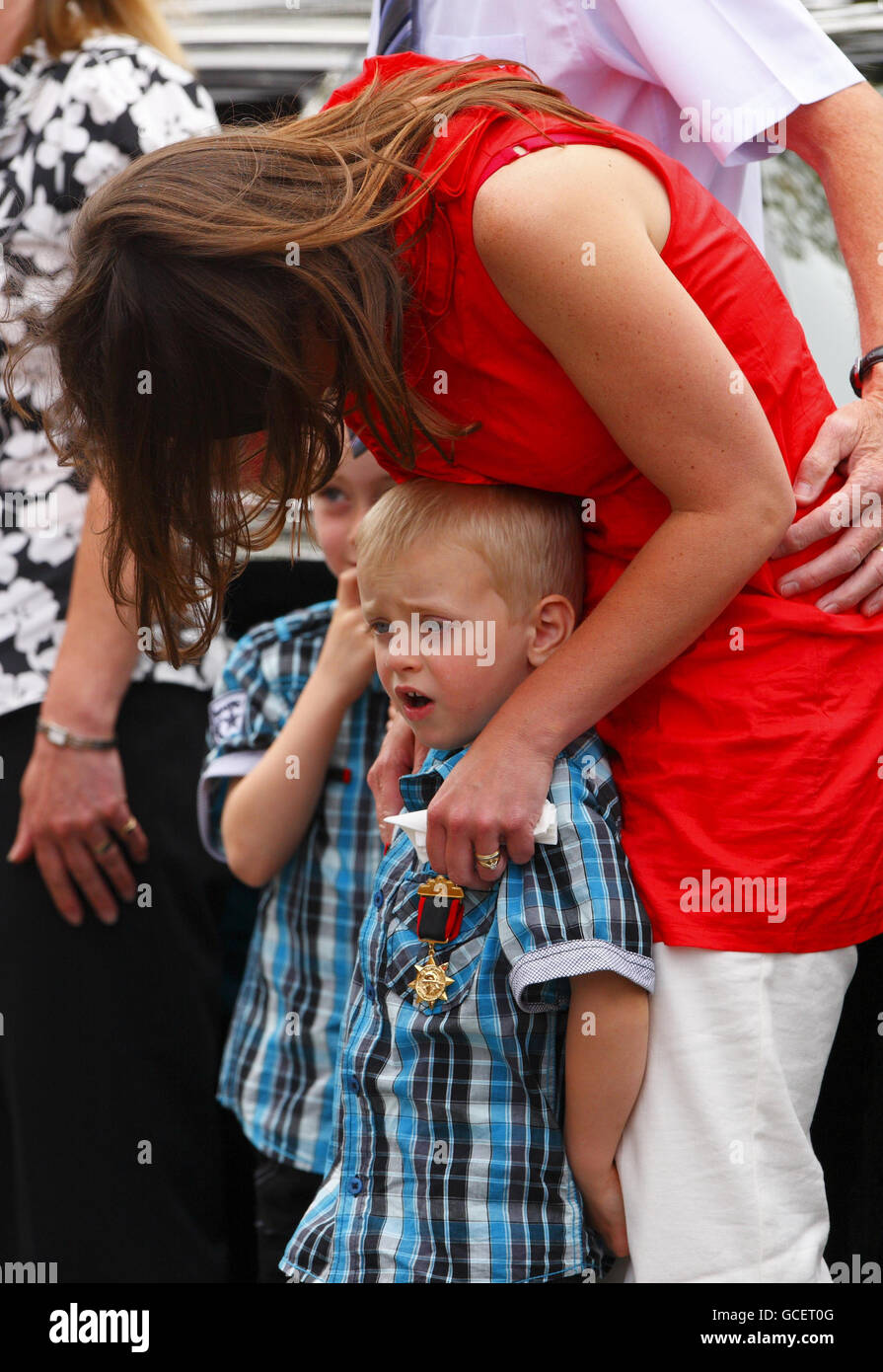 Clara Shears, vedova del vigile del fuoco dell'Hampshire James Shears, attende con i suoi figli Frankie, 5, (dietro), e Ruben, 4, Entrambi indossano le medaglie del padre alla chiesa di St Georges a Poole, Dorset, per i funerali del marito morto durante un incendio a Southampton tre settimane fa. Foto Stock