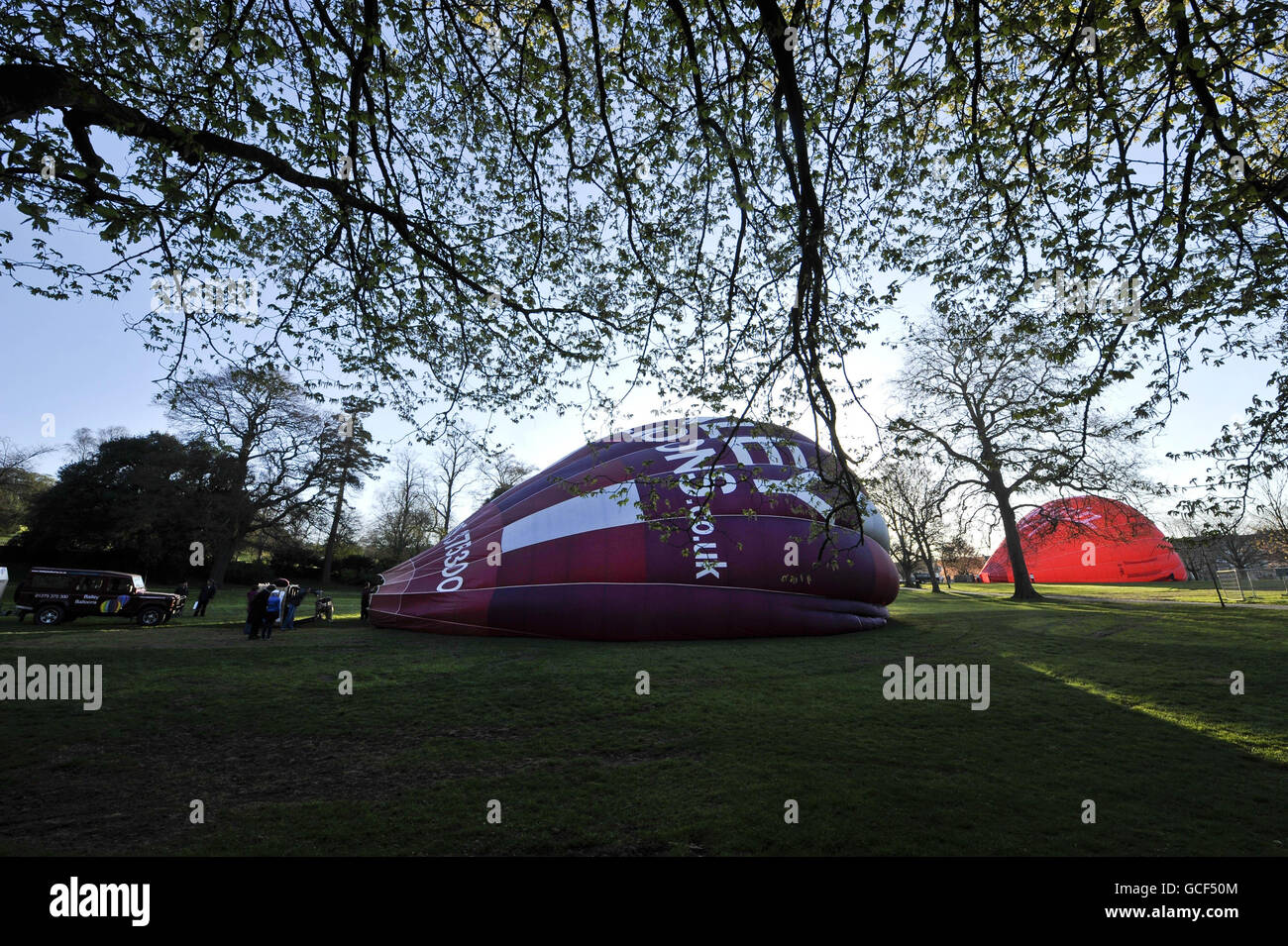 I palloncini ad aria calda vengono gonfiati a terra prima di un volo in una mattinata di primavera soleggiata a Victoria Park, Bath dopo che il divieto di volo motorizzato è stato revocato. Foto Stock