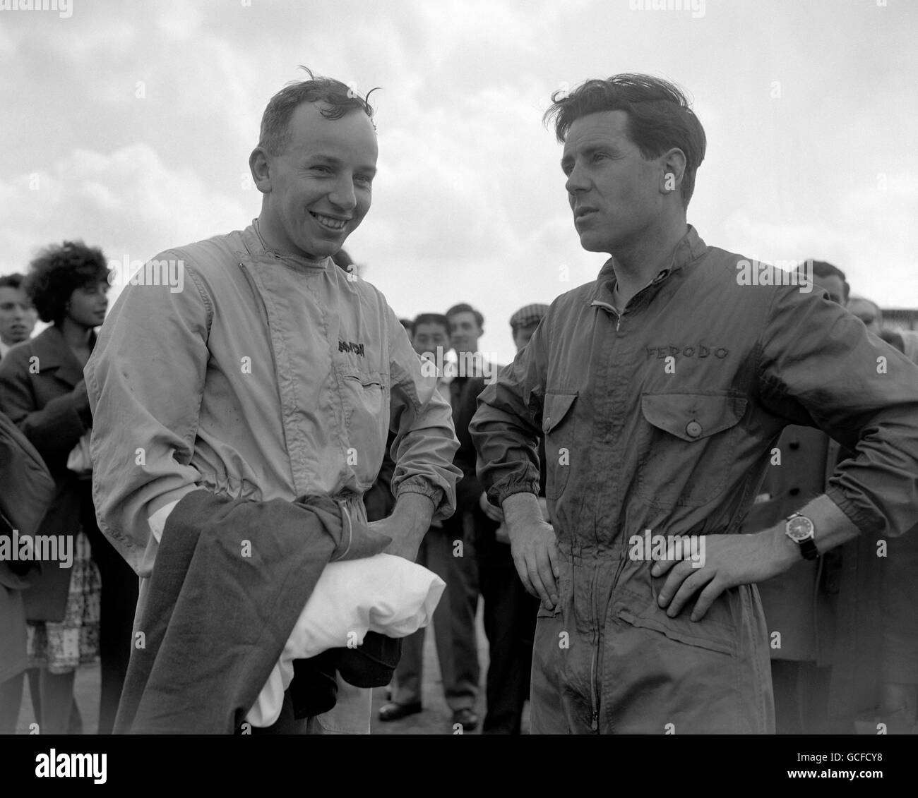 John Surtees (a sinistra) e Geoff Duke, che entrambi hanno avuto campionati del mondo motociclistico, stanno prendendo in giro le corse automobilistiche. Si sono incontrati sulla pista di Silverstone nel Northamptonshire, dove entrambi hanno partecipato alla riunione del 14 maggio. Foto Stock
