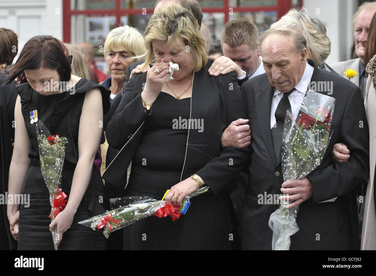 I Mourners guardano come le audizioni che contengono le barene di Sapper Daryn Roy, del corporale di Lance Barry Buxton e del corporale Harvey Holmes passano attraverso la città di Wootton Bassett dopo il loro rimpatrio a RAF Lyneham in Wiltshire. Foto Stock