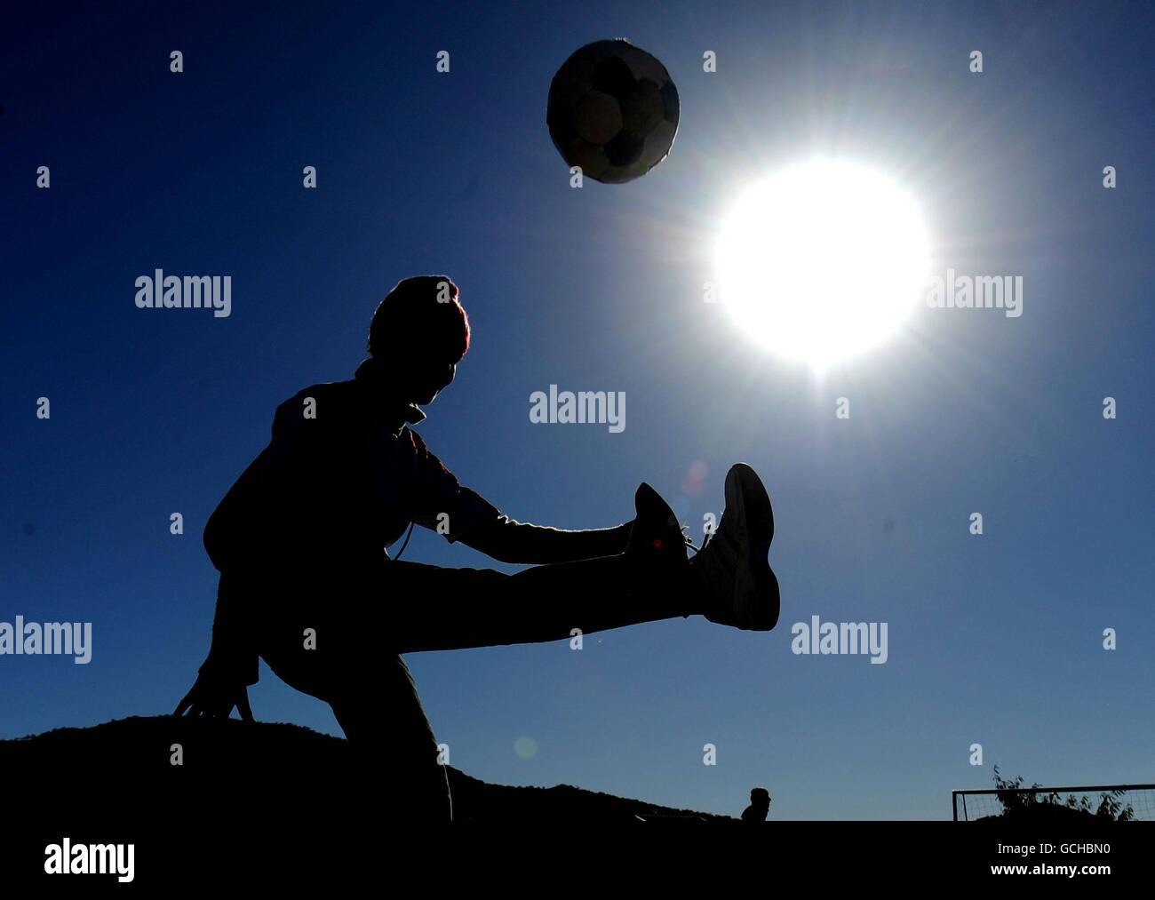 Calcio - Coppa del mondo FIFA Sud Africa 2010 - Inghilterra i giocatori visitano Local Township - Rustenburg. Un locale gioca un calcio mentre Michael Dawson e Matthew Upson in Inghilterra visitano Tlhabane Township nei pressi di Rustenburg, Sudafrica. Foto Stock