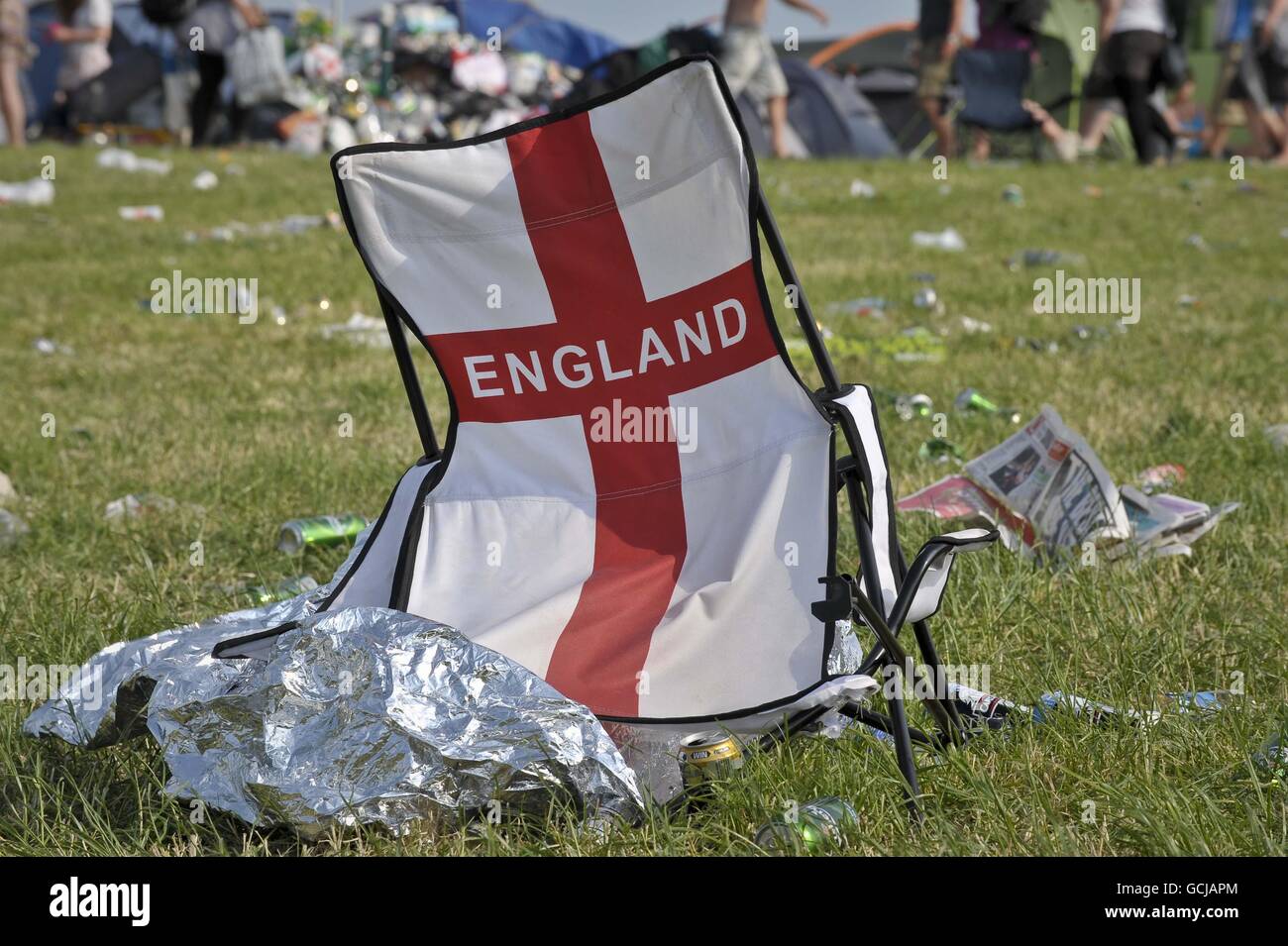Una sedia dell'Inghilterra rotta è lasciata tra i rifiuti sul campo dove la partita di calcio della Coppa del mondo dell'Inghilterra contro la Germania è stata mostrata su un grande schermo durante il festival di Glastonbury 2010 presso la Worthy Farm di Pilton, Somerset. Foto Stock