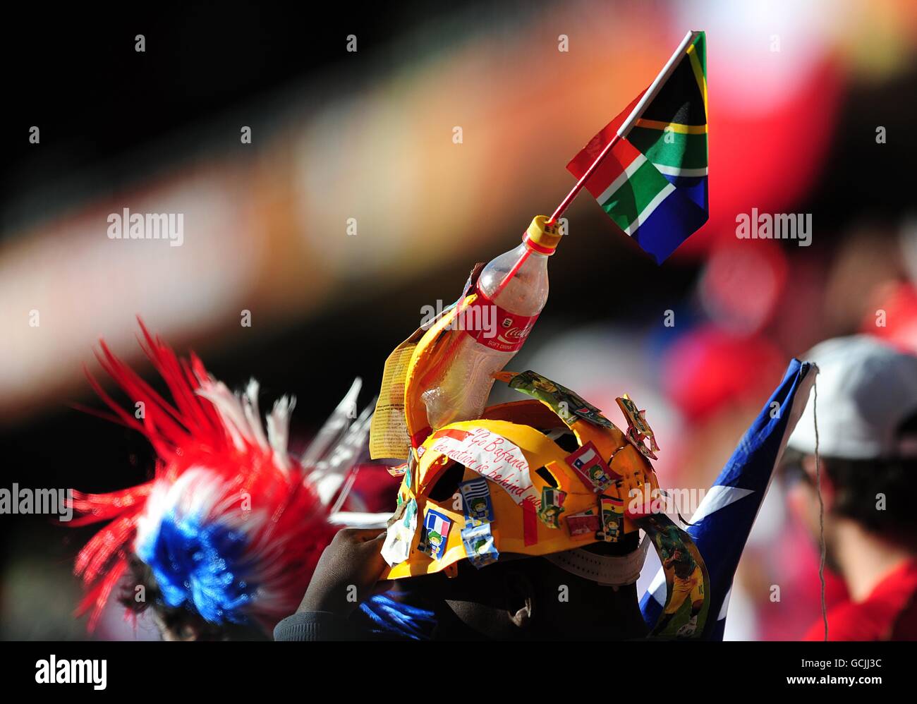 Un elmetto decorato con una bottiglia di coca-cola, una bandiera e alcuni adesivi indossati da un ventilatore nei supporti. Foto Stock