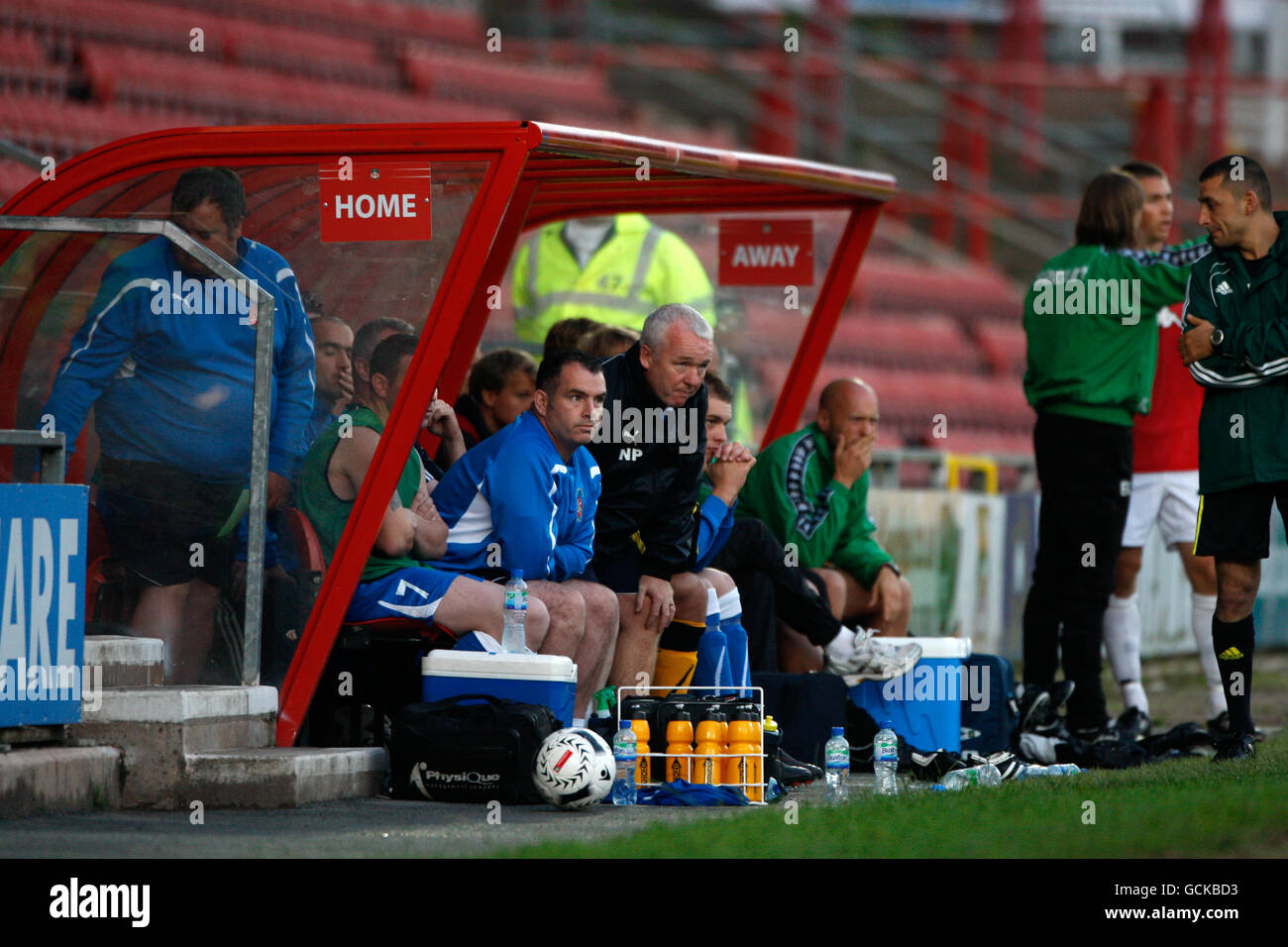 Bangor City manager Nev Powell con il suo coaching staff su il banco Foto Stock