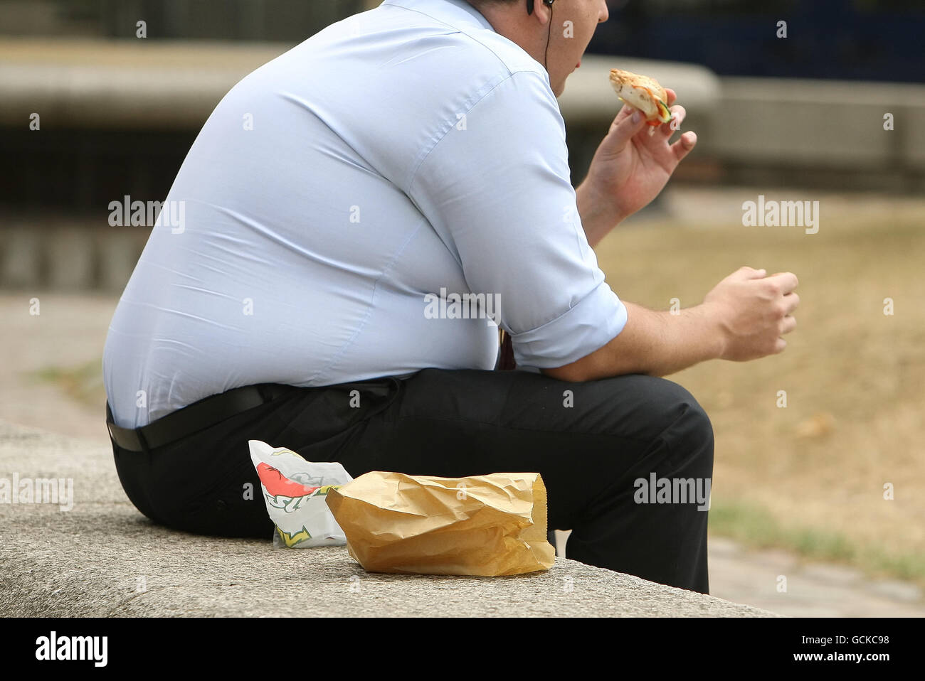Un uomo in sovrappeso mangia fast food. Foto Stock